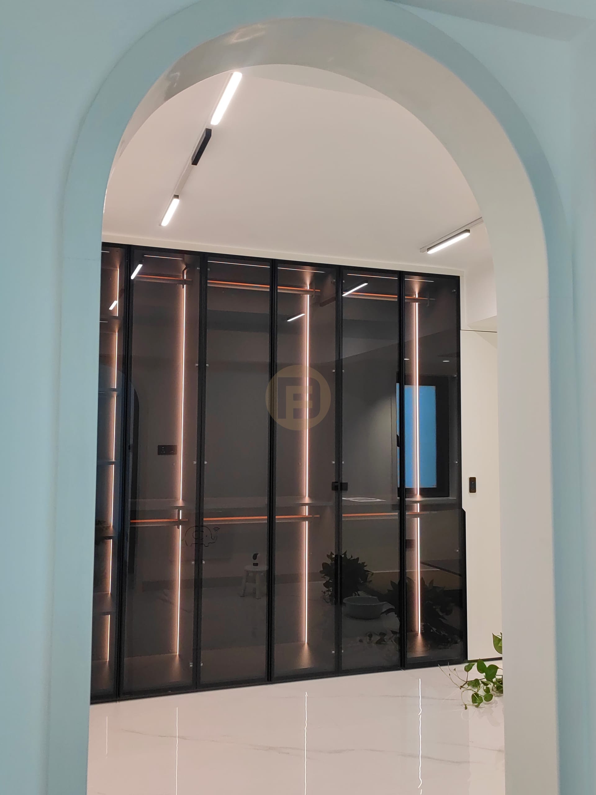 Arched opening onto a walk-in closet with smoked-glass doors and warm LED lighting