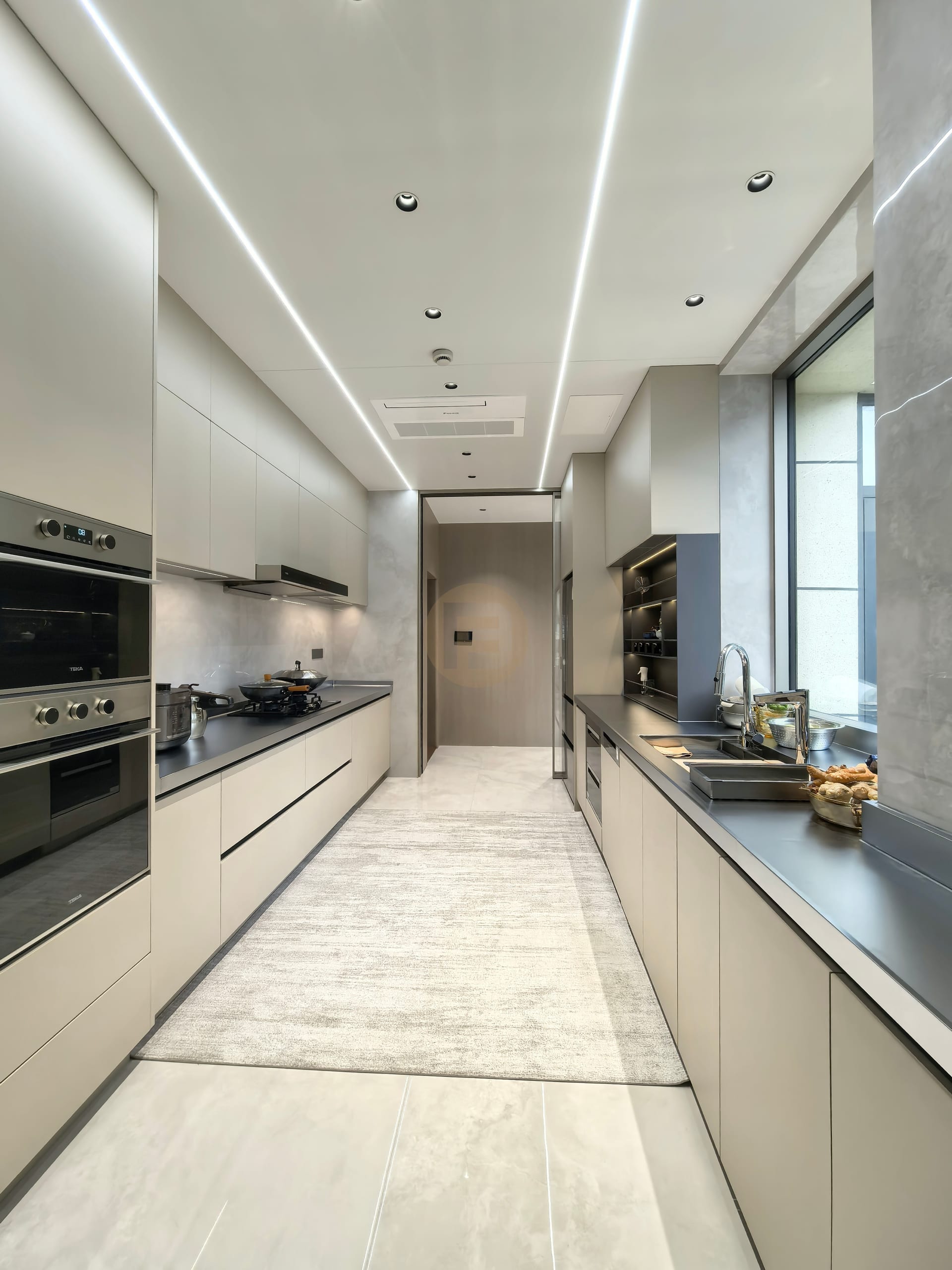 Galley kitchen with champagne stainless steel cabinetry, black worktops and linear LED ceiling lights