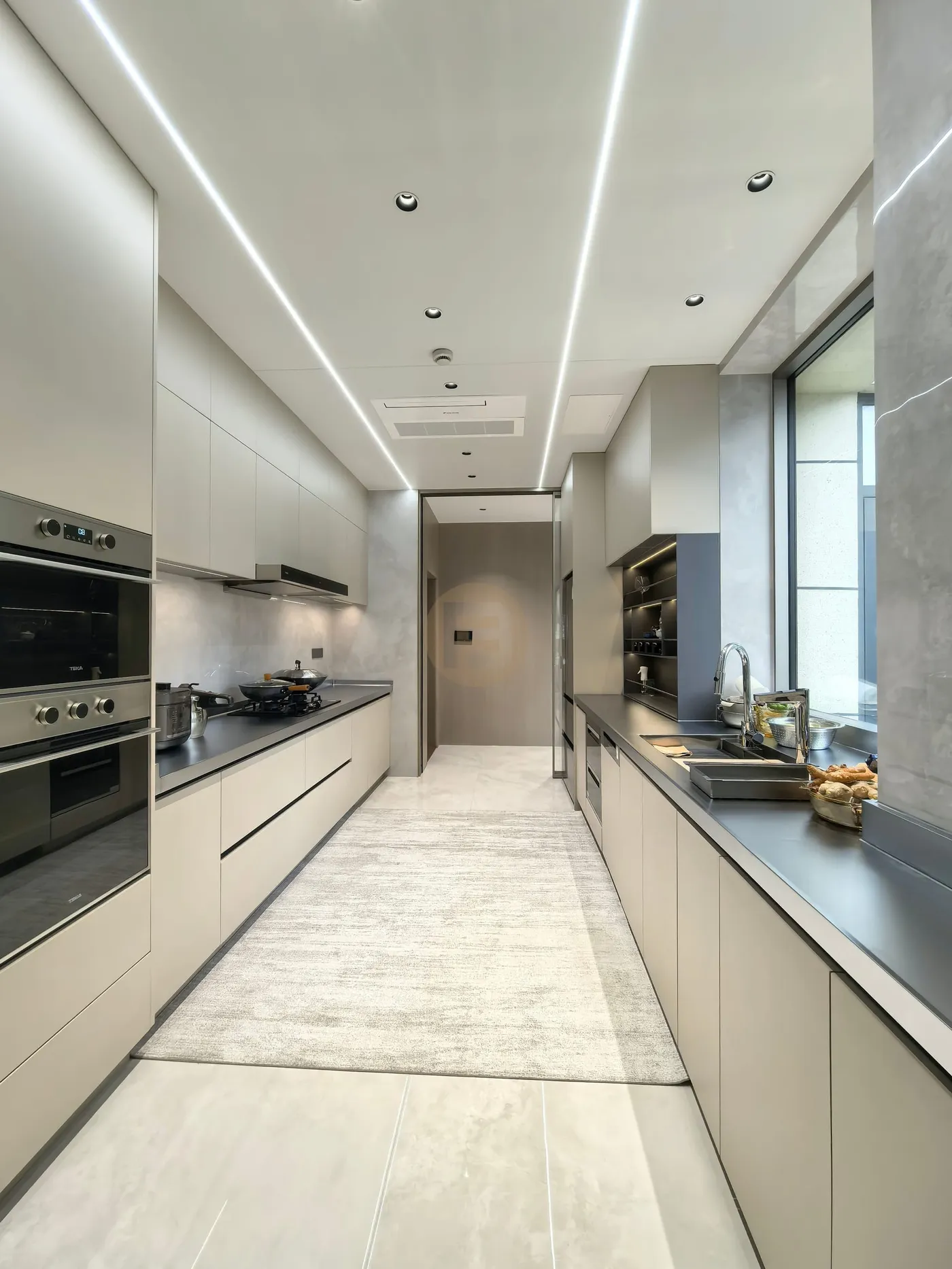 Galley kitchen with champagne stainless steel cabinetry, black worktops and linear LED ceiling lights