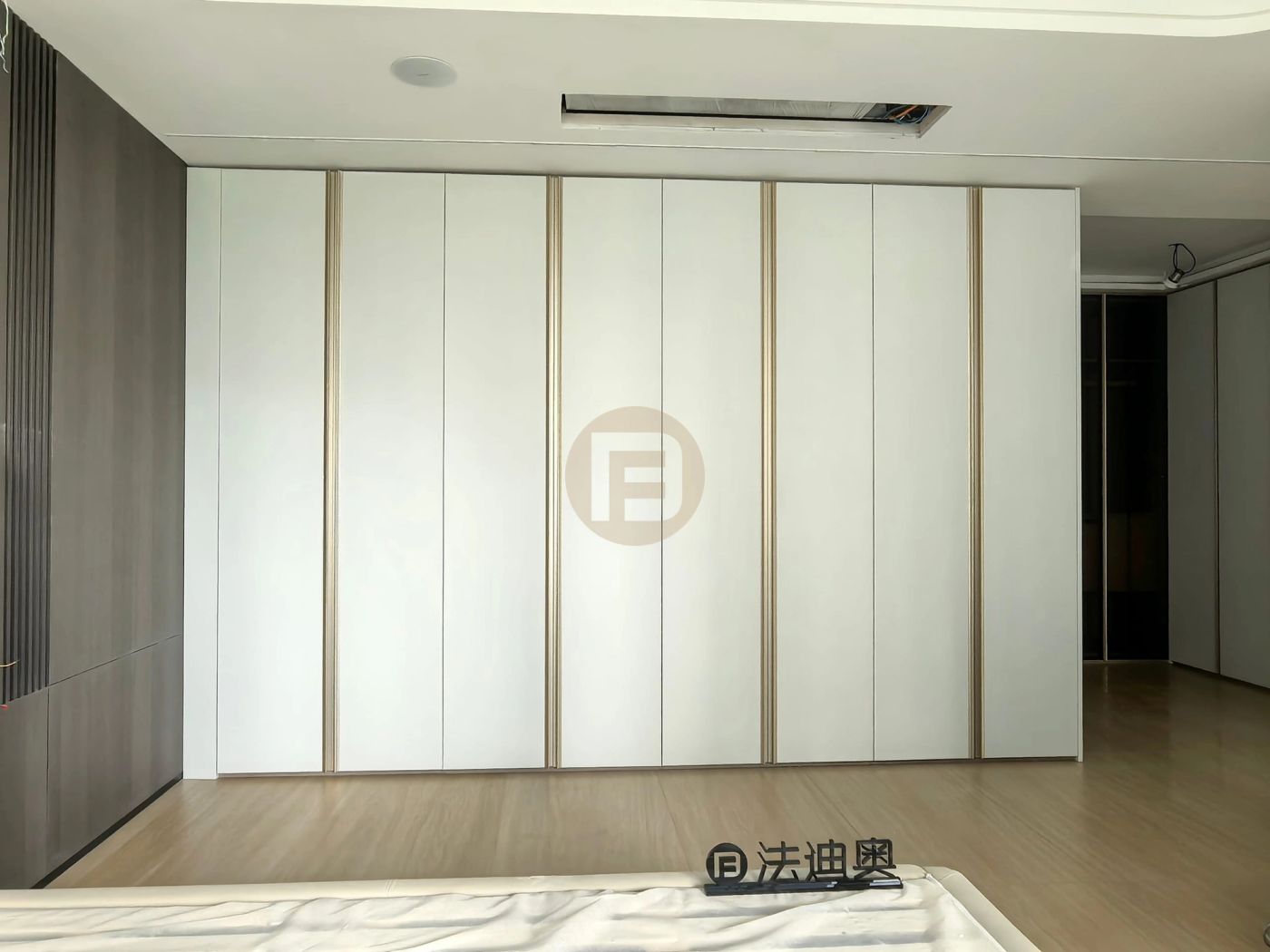 Primary bedroom wardrobe wall of matte white stainless steel doors with slim champagne-gold trim