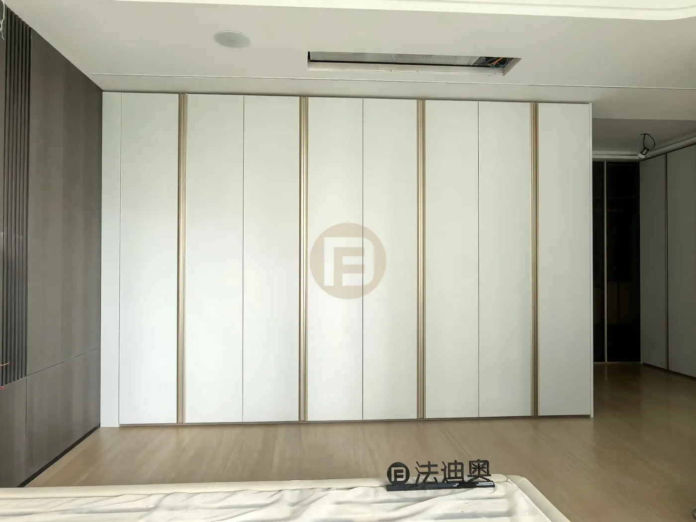 Primary bedroom wardrobe wall of matte white stainless steel doors with slim champagne-gold trim