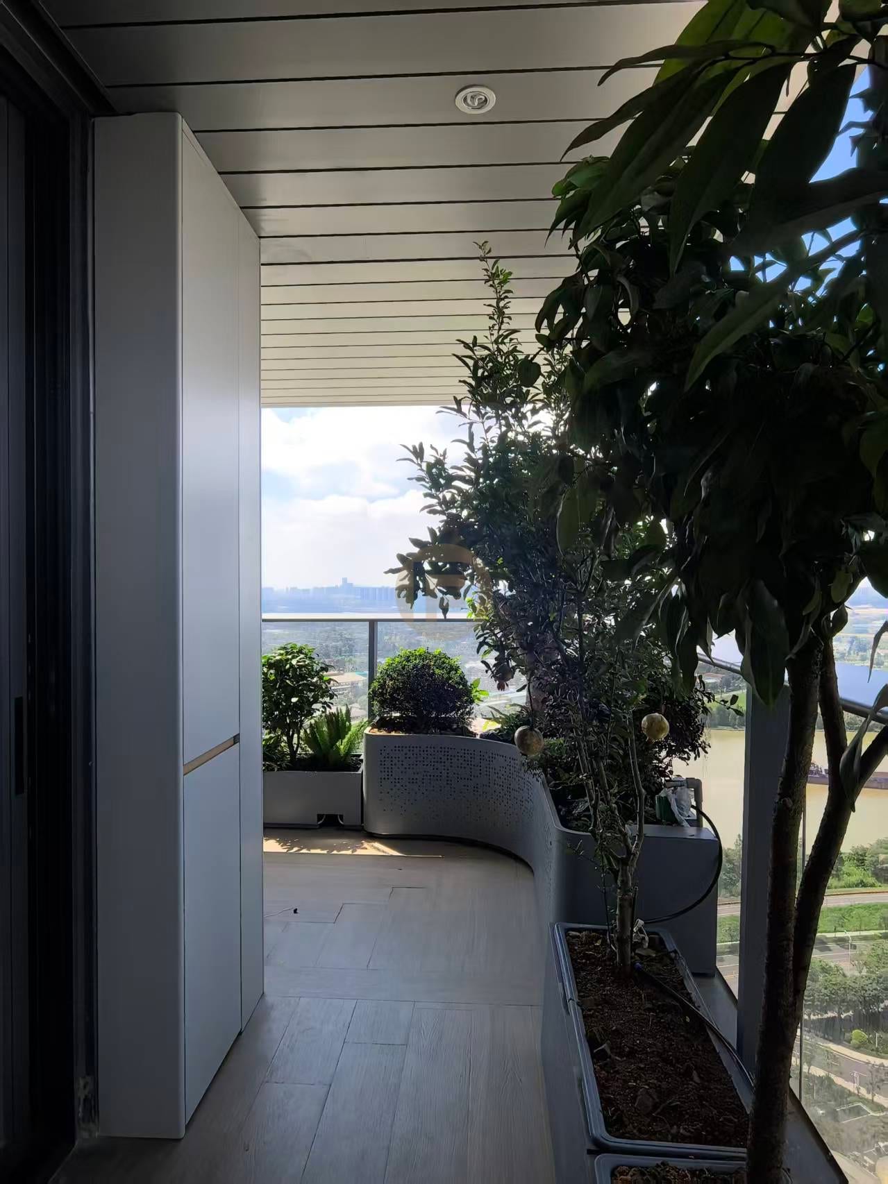 Tall white stainless steel storage cabinet on a planted balcony with an open water view