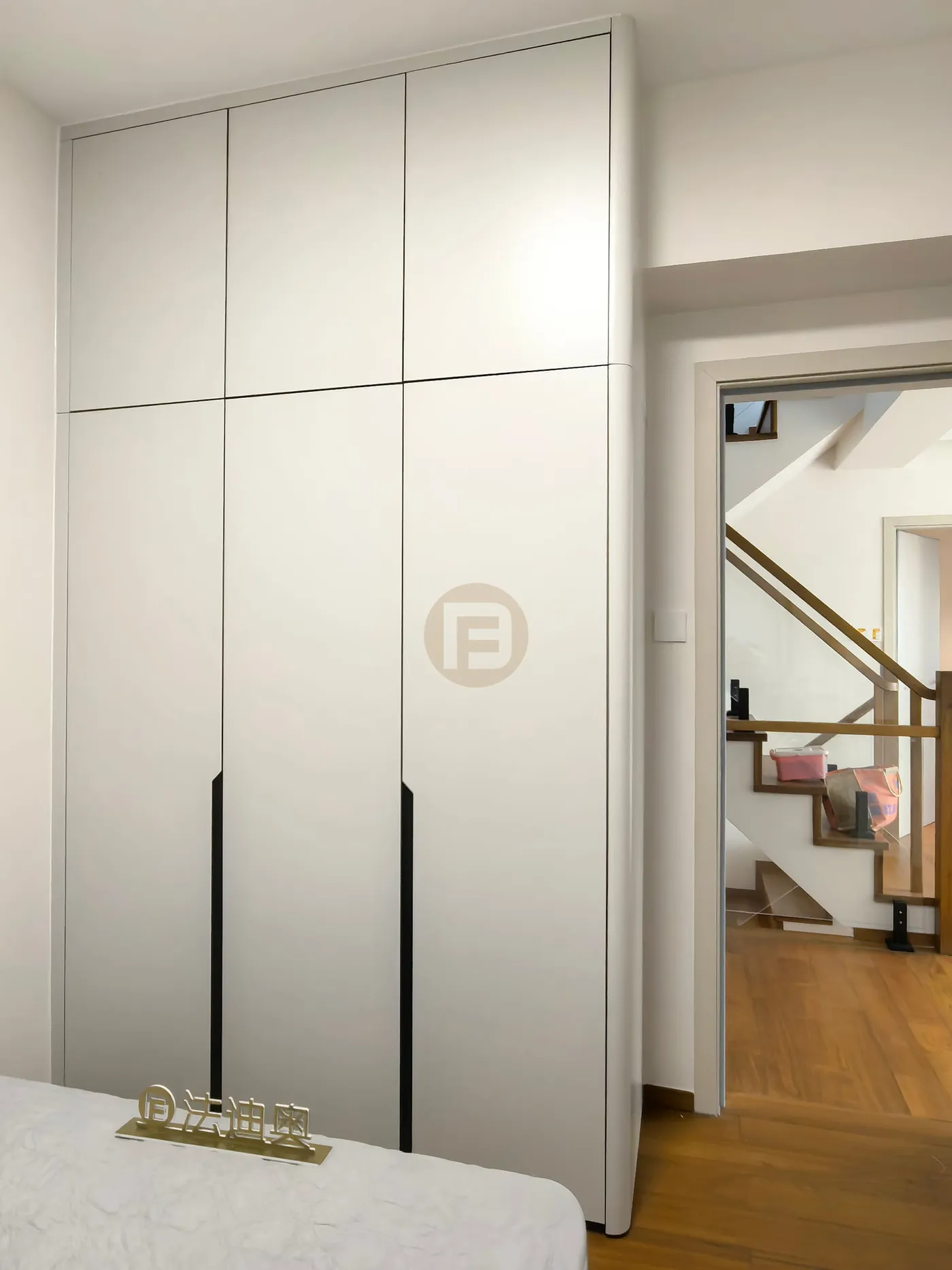 Floor-to-ceiling bedroom wardrobe in matte white stainless steel with slim black handle reveals