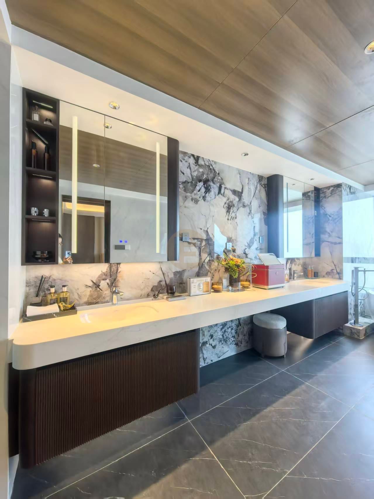 Long double vanity with fluted walnut-tone drawers against a bookmatched marble feature wall