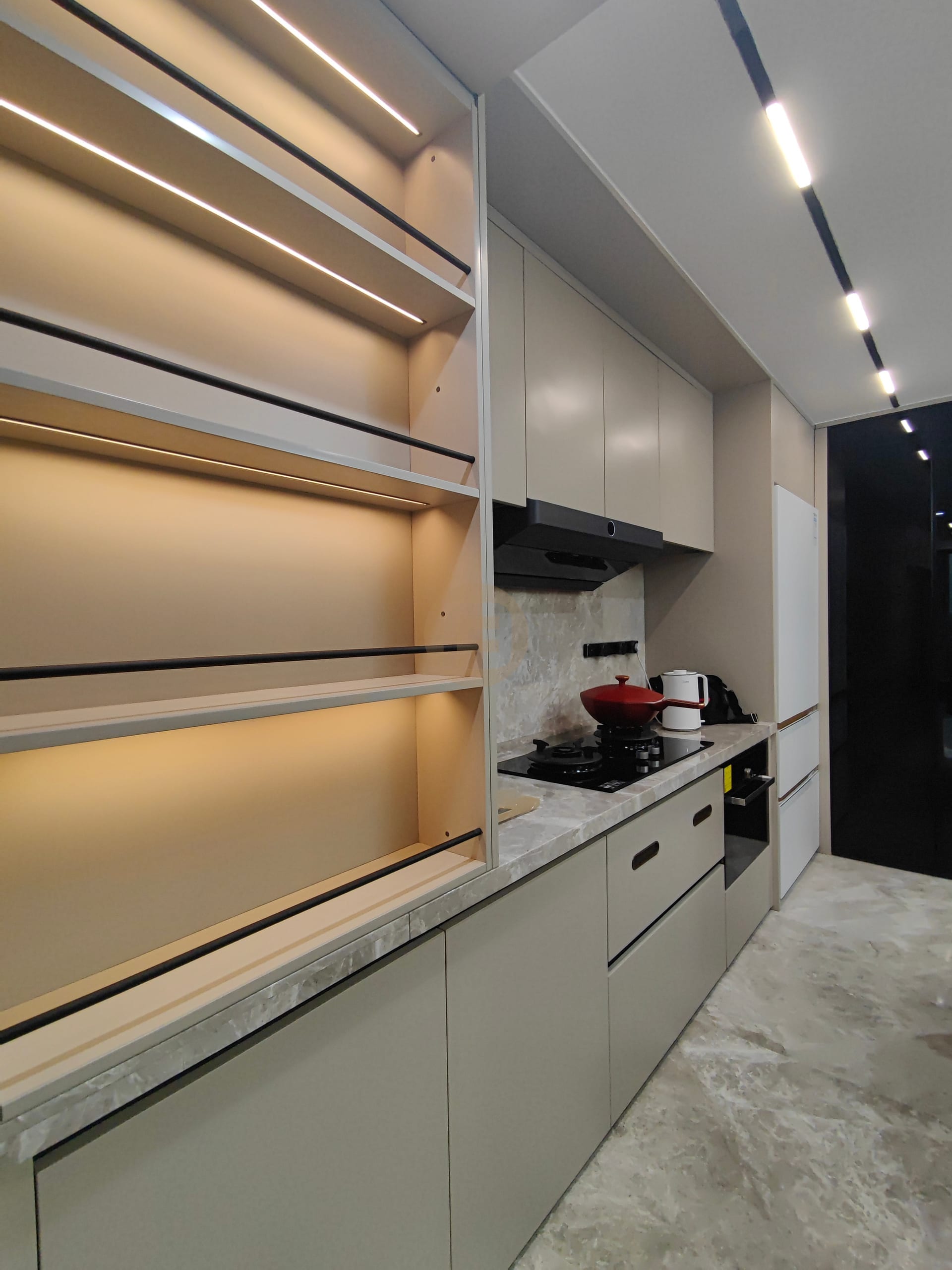 Greige stainless steel kitchen run with backlit open shelving, marble worktop and integrated black hob