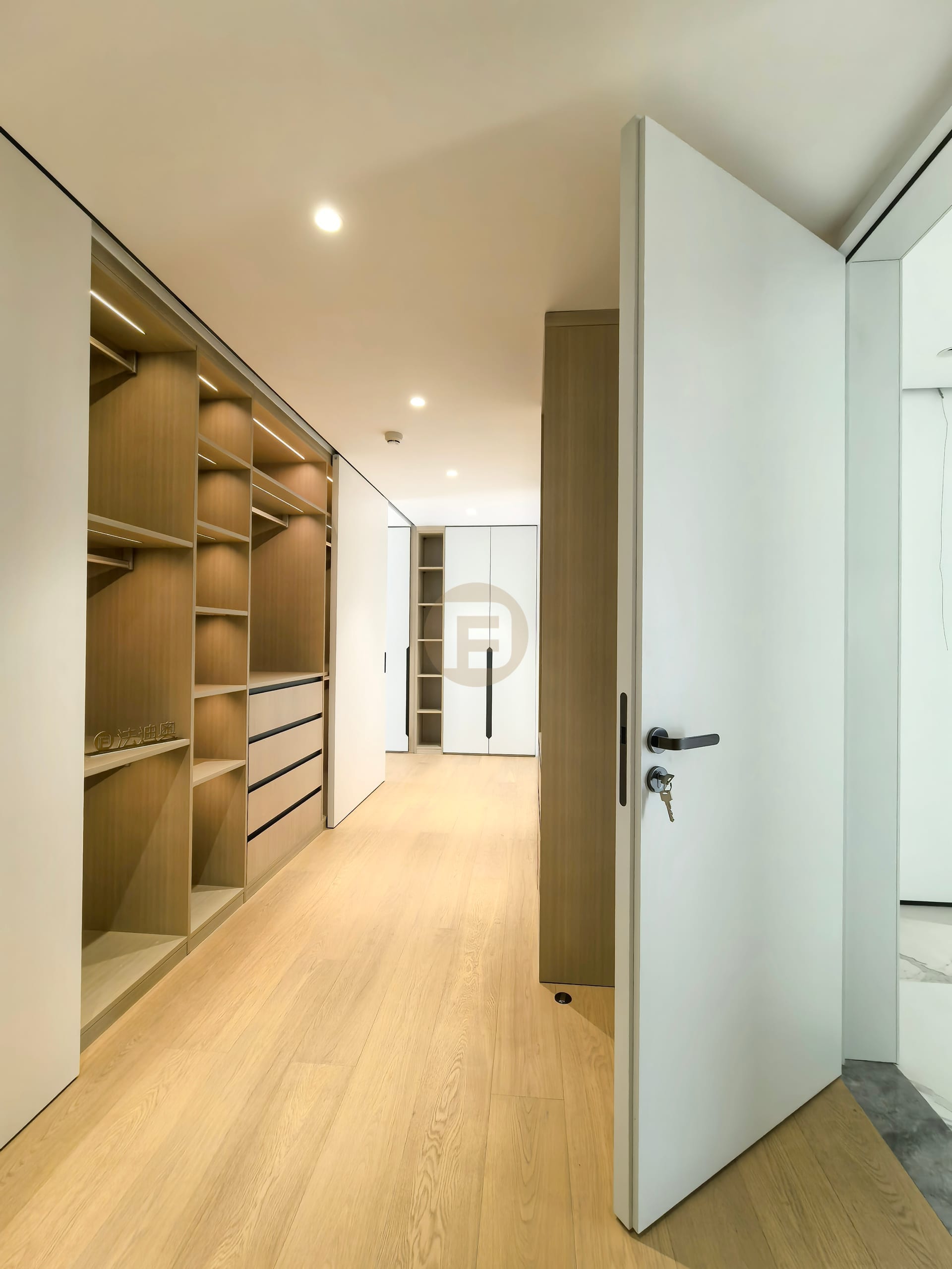 Dressing corridor of open oak shelving leading to white floor-to-ceiling wardrobes