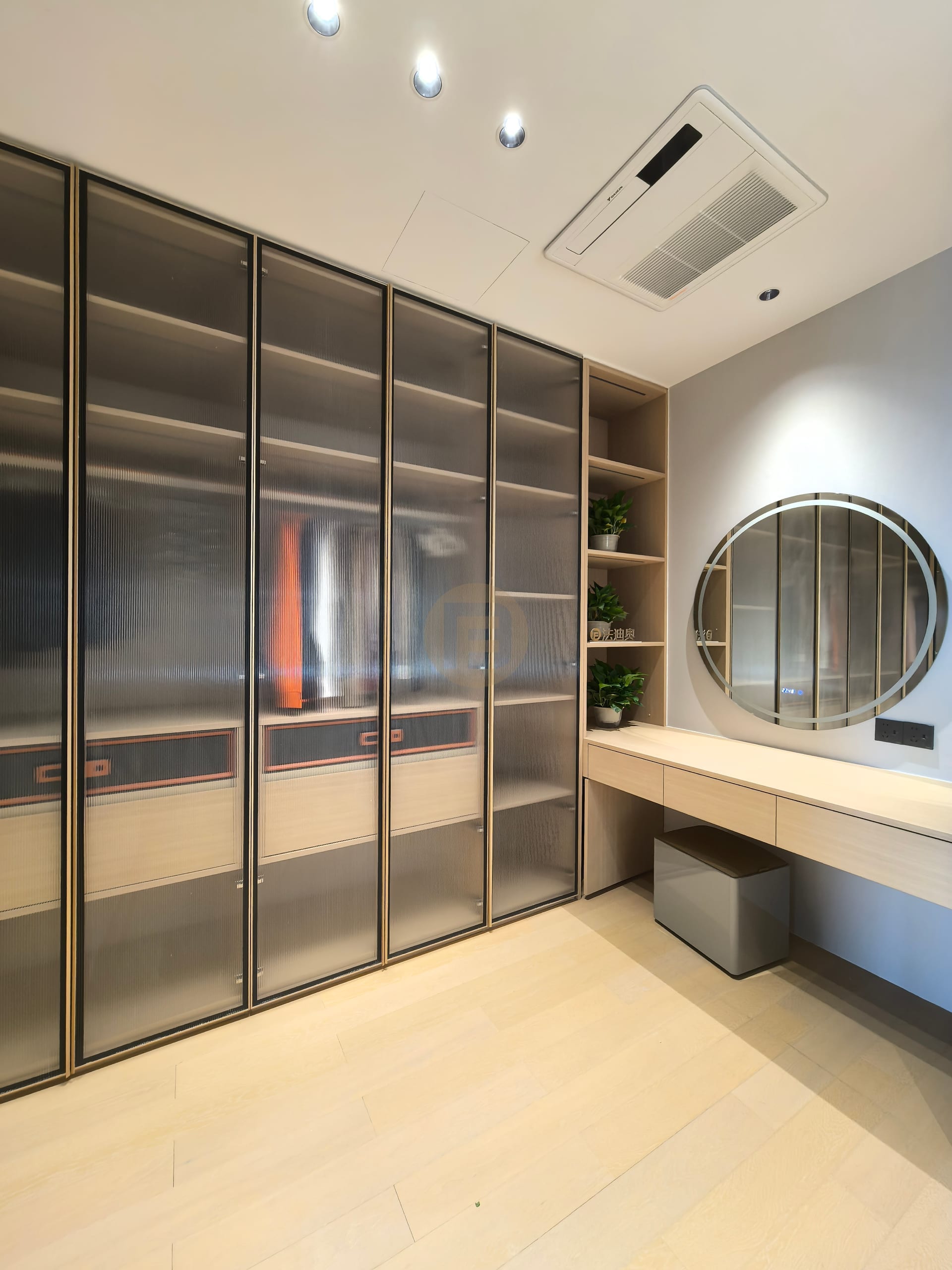 Dressing room lined with smoked ribbed-glass wardrobes and a wall-hung vanity with round mirror