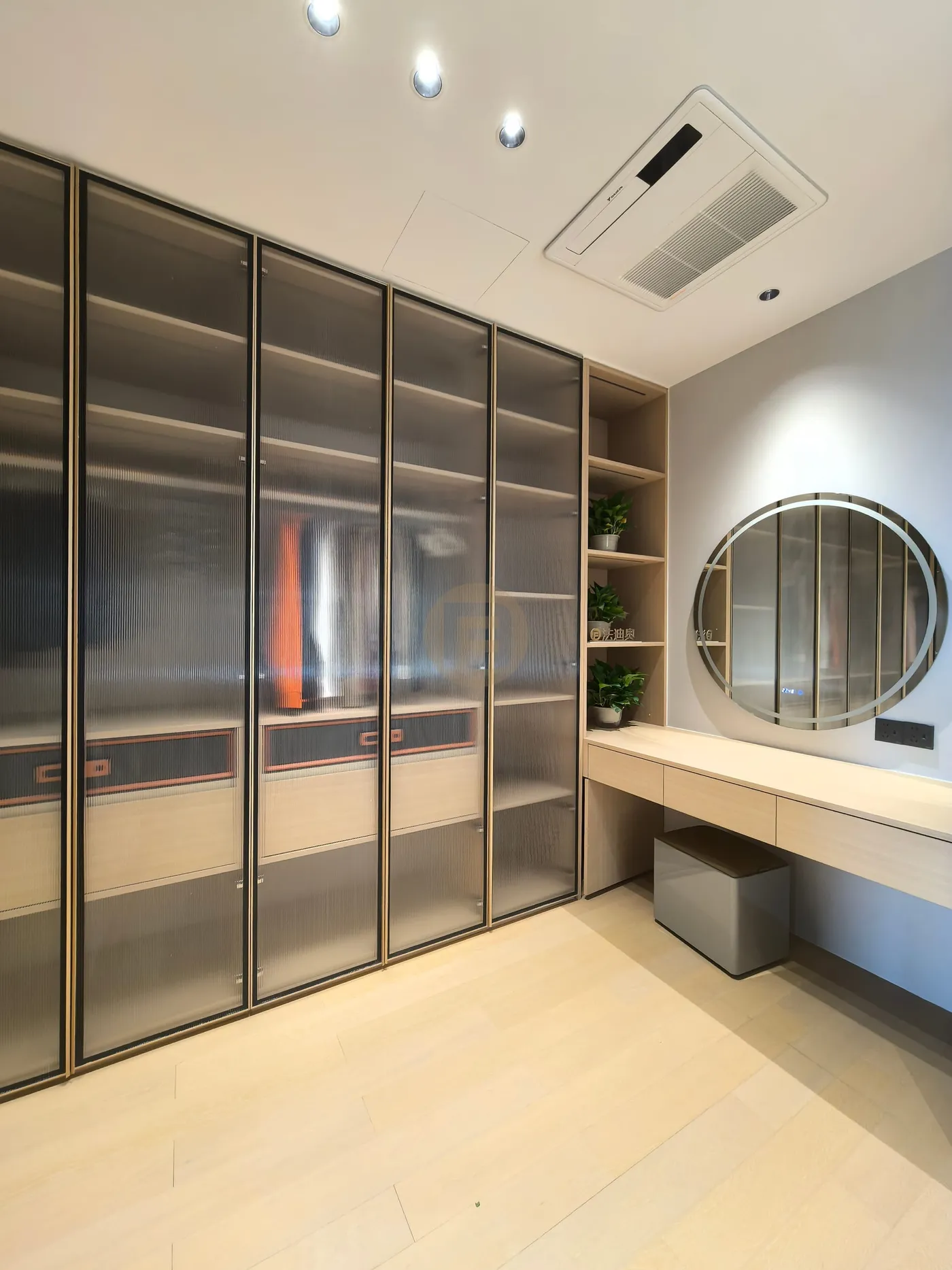 Dressing room lined with smoked ribbed-glass wardrobes and a wall-hung vanity with round mirror