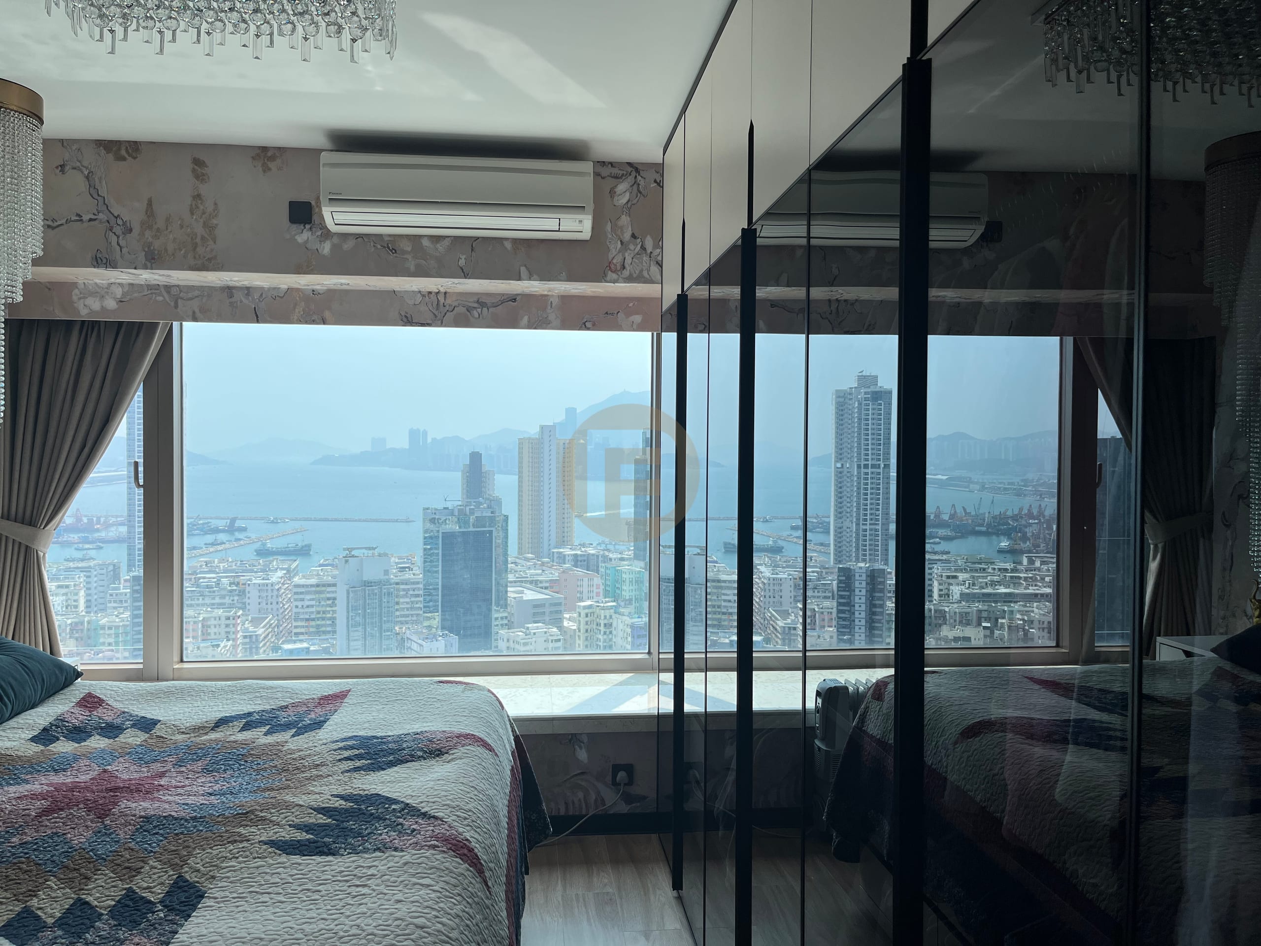 Bedroom wardrobes with dark glass fronts reflecting the harbour view beside the bed