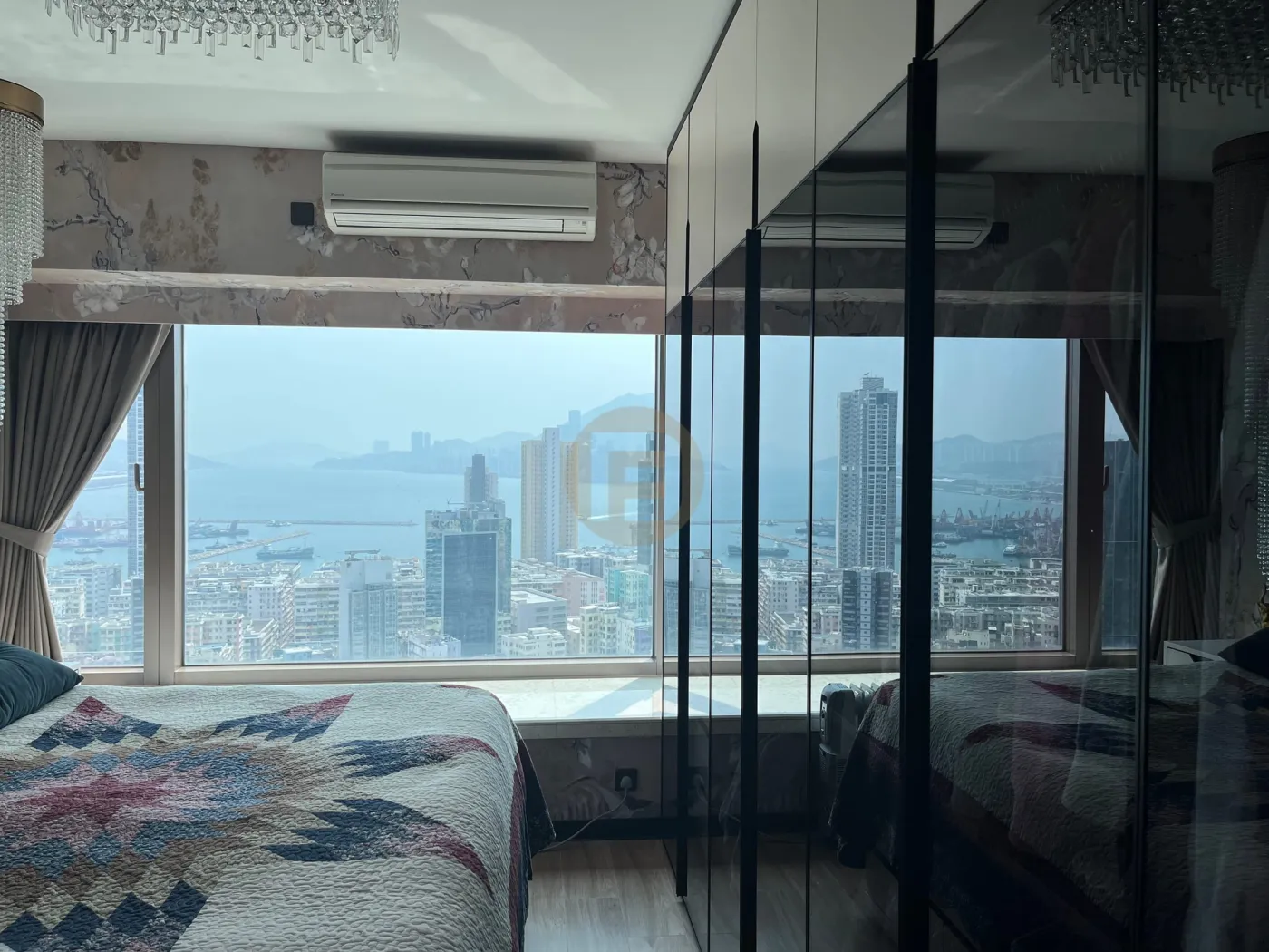 Bedroom wardrobes with dark glass fronts reflecting the harbour view beside the bed