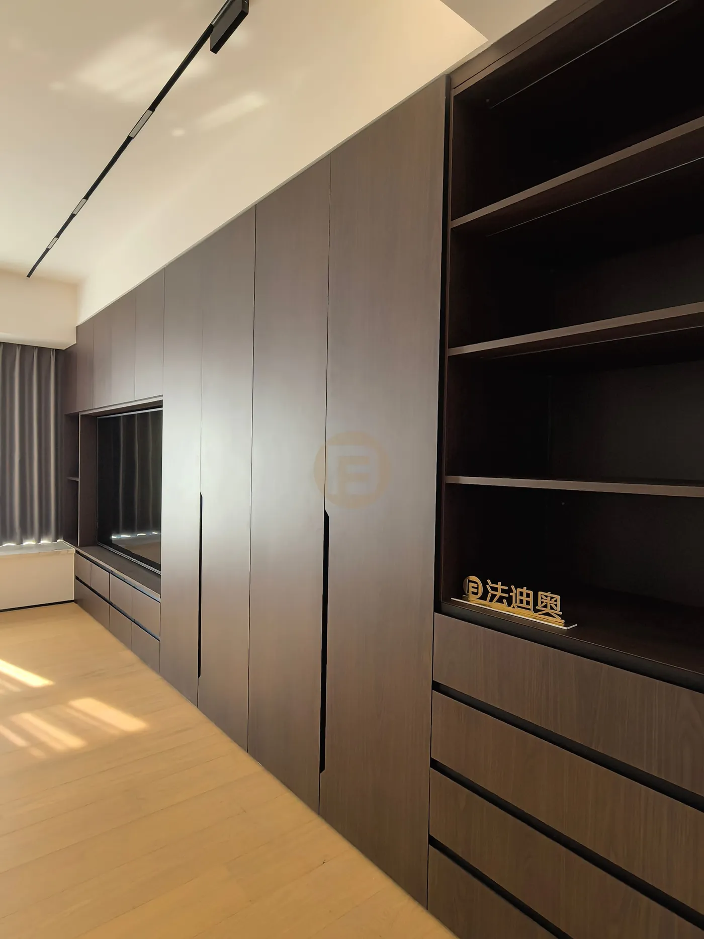 Walnut-toned stainless steel wardrobe wall with recessed media niche and open shelving