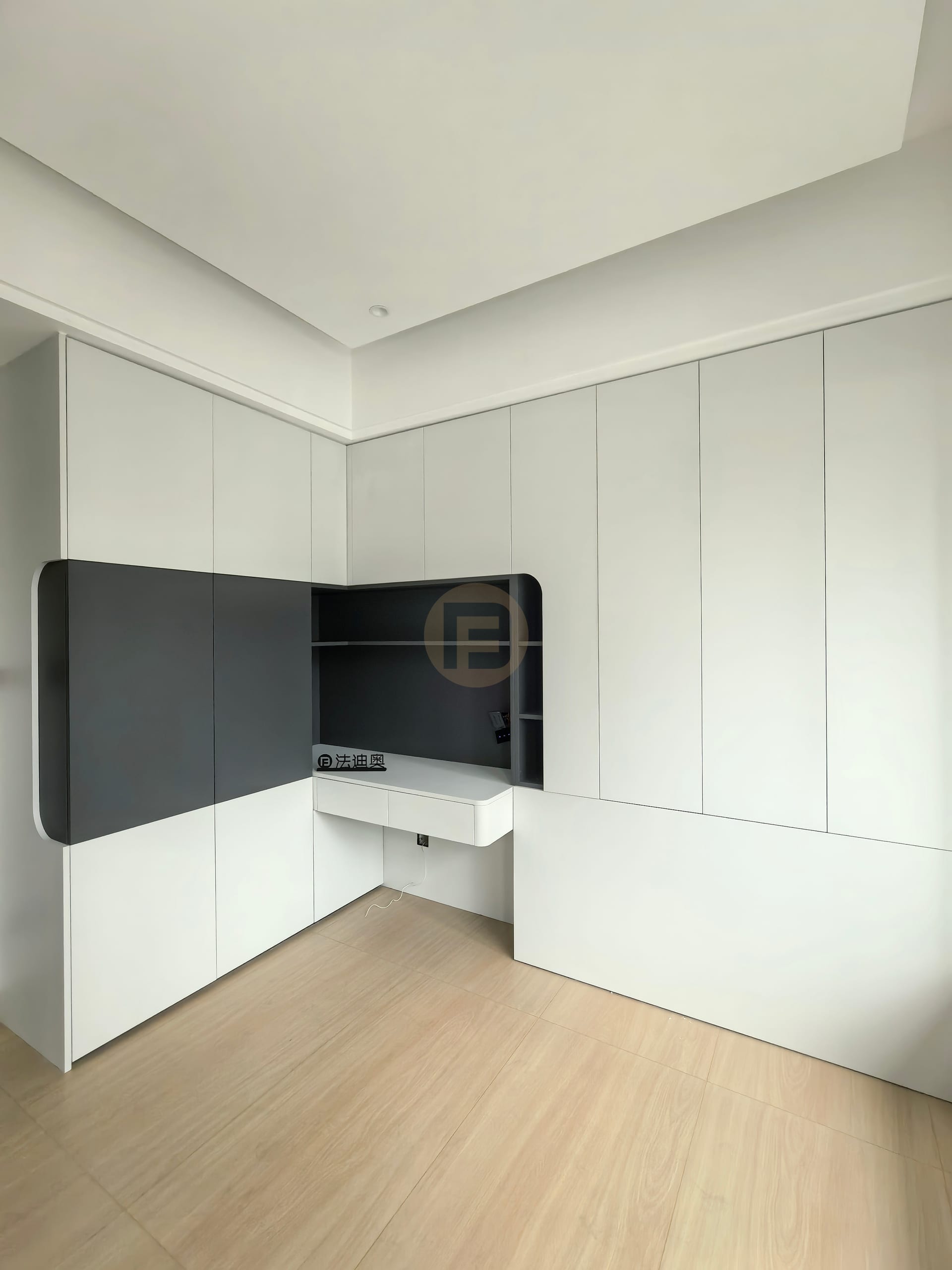 White cabinetry wall opening into a charcoal grey study niche with floating desk and open shelves