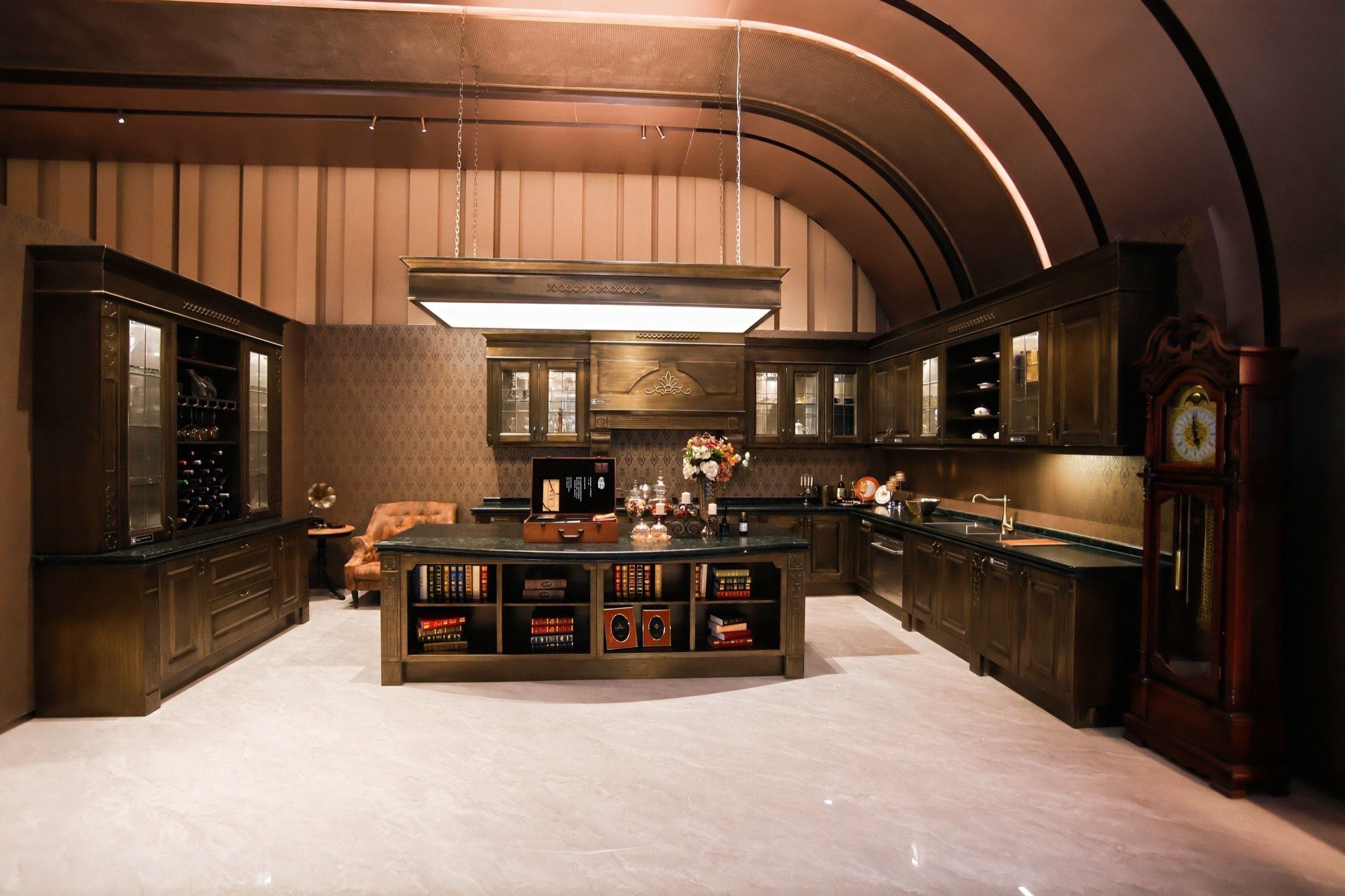 Warm stainless steel kitchen display beneath a curved timber-toned ceiling in the Fadior showroom.