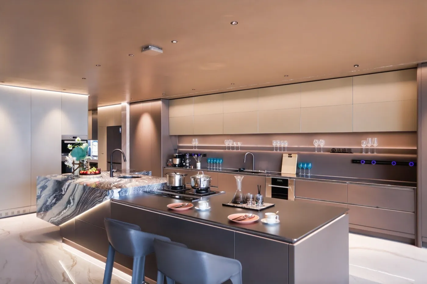 Warm metallic kitchen with a central stone island and integrated full-height cabinetry.