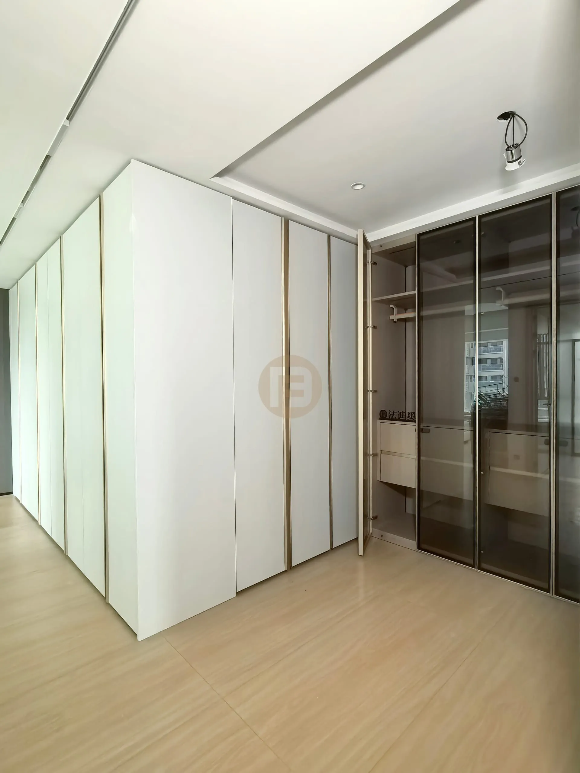 Matte white stainless steel cabinetry volume with champagne trim beside a smoked-glass walk-in wardrobe