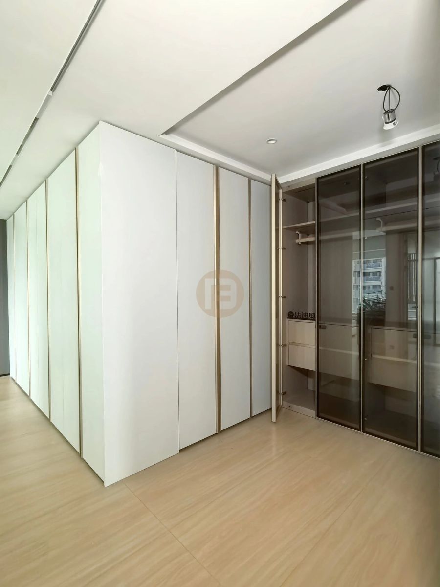 Matte white stainless steel cabinetry volume with champagne trim beside a smoked-glass walk-in wardrobe