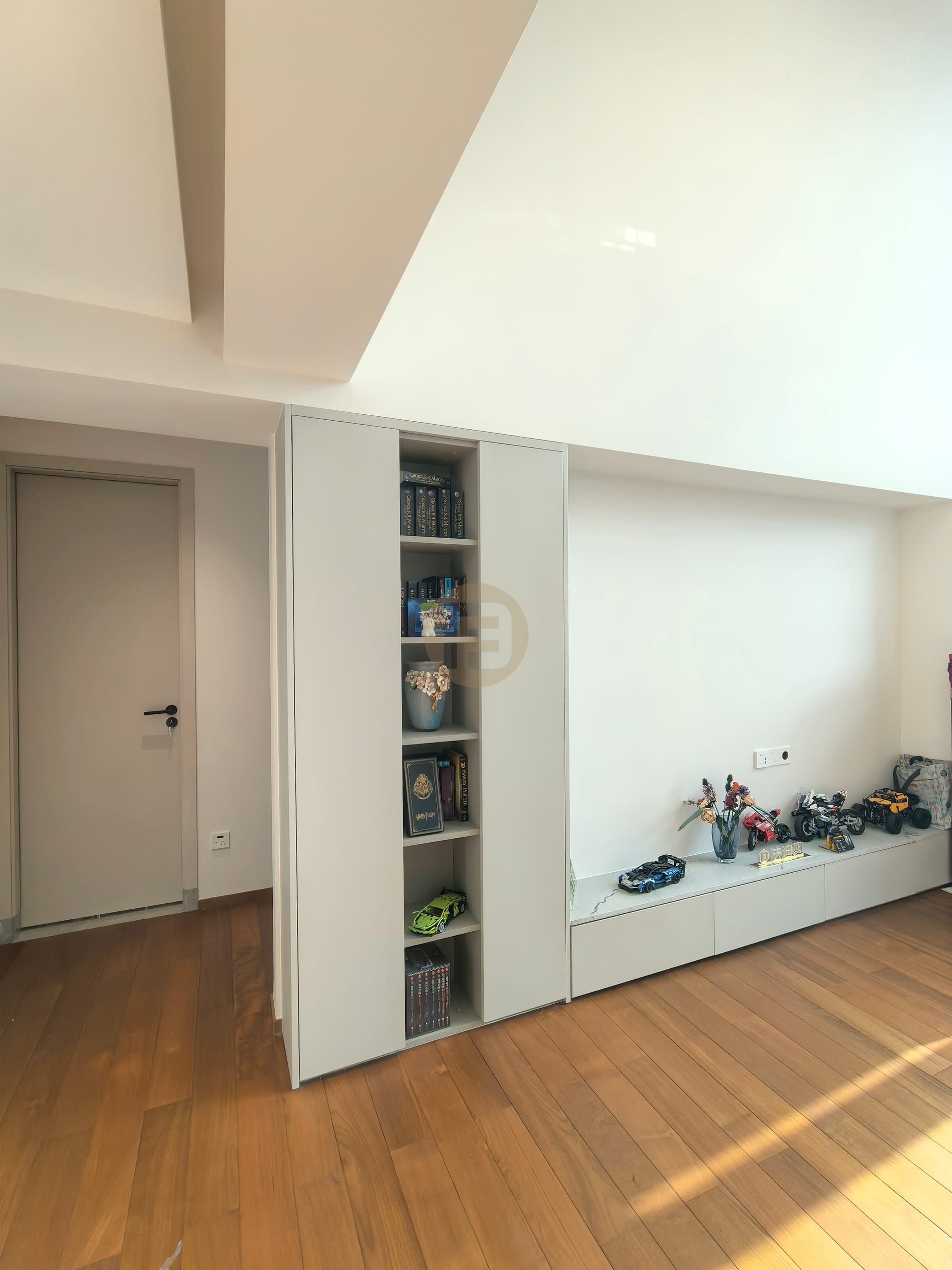 Loft family area with built-in bookshelf tower and long low stainless steel media cabinets