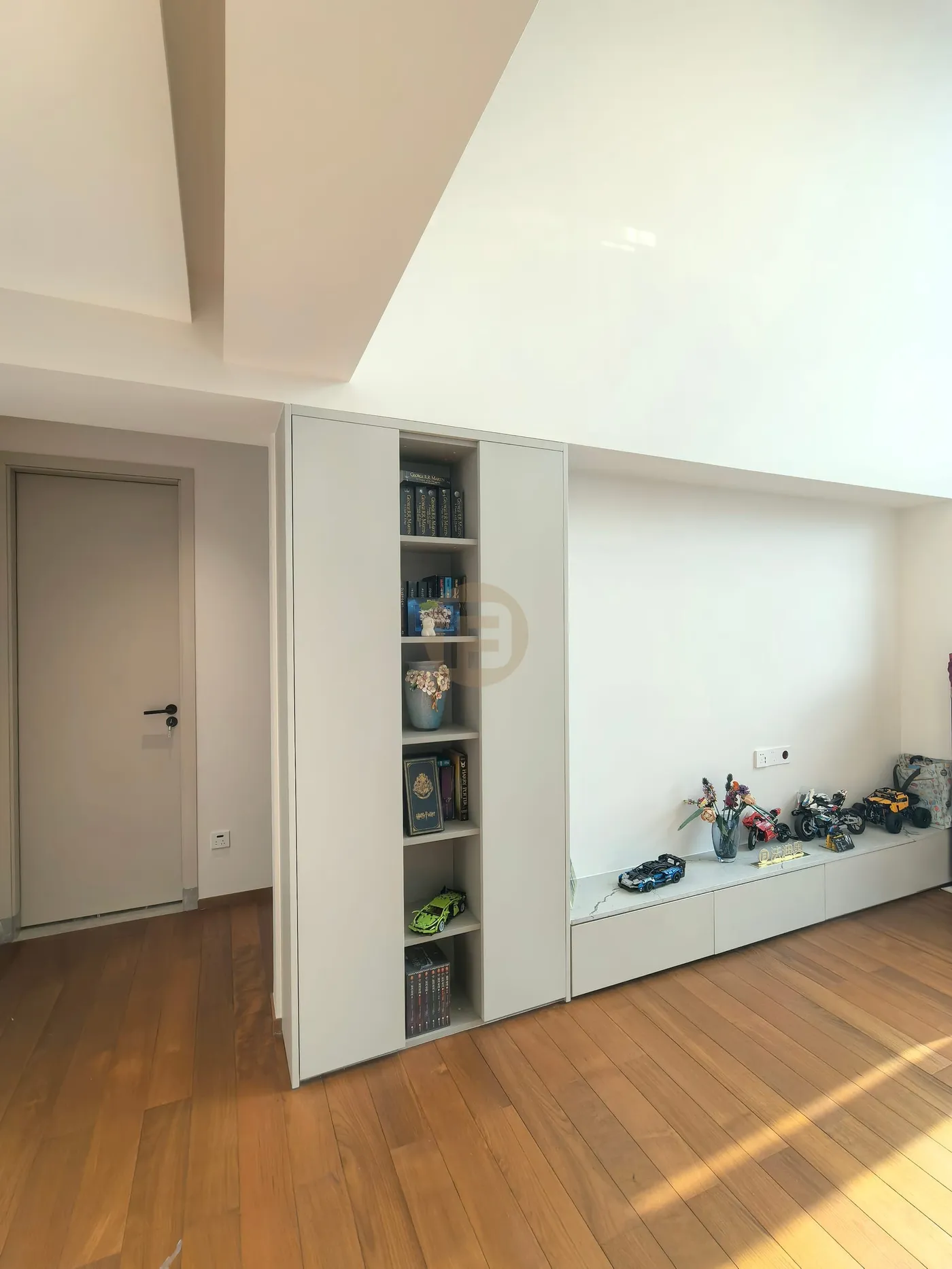 Loft family area with built-in bookshelf tower and long low stainless steel media cabinets