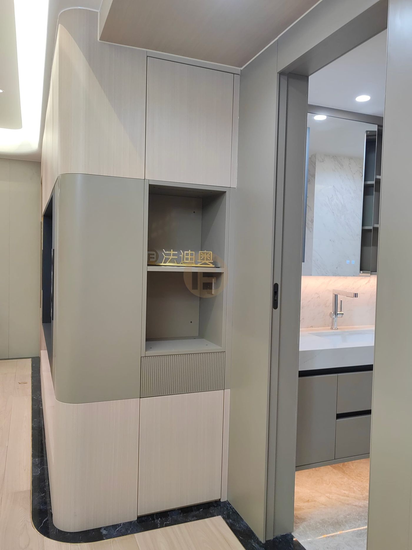 Curved hallway cabinet with display niche beside a pocket door opening to the vanity room
