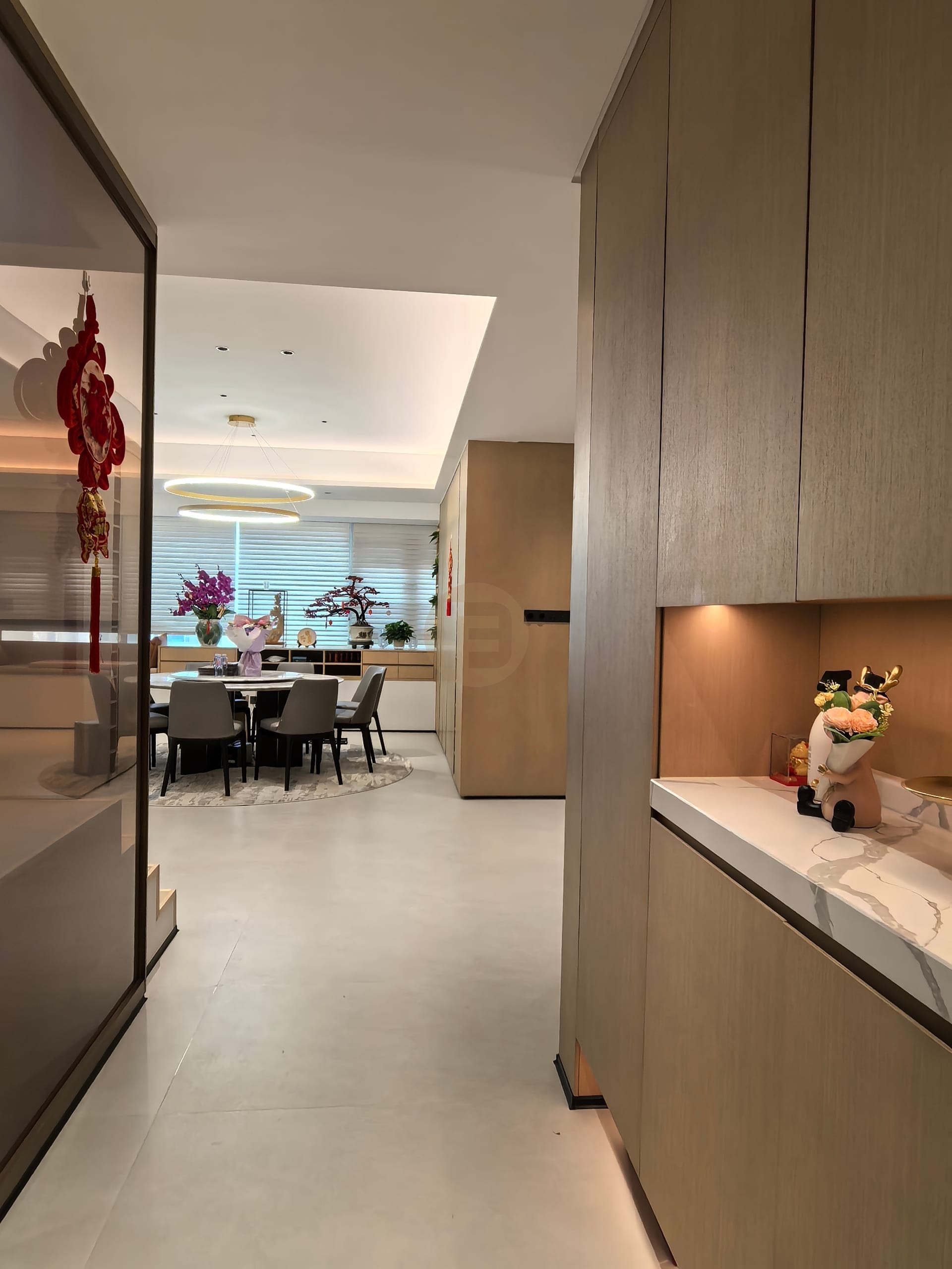 Full-height woodgrain cabinetry and a stone-topped sideboard with lit niches flanking the dining area
