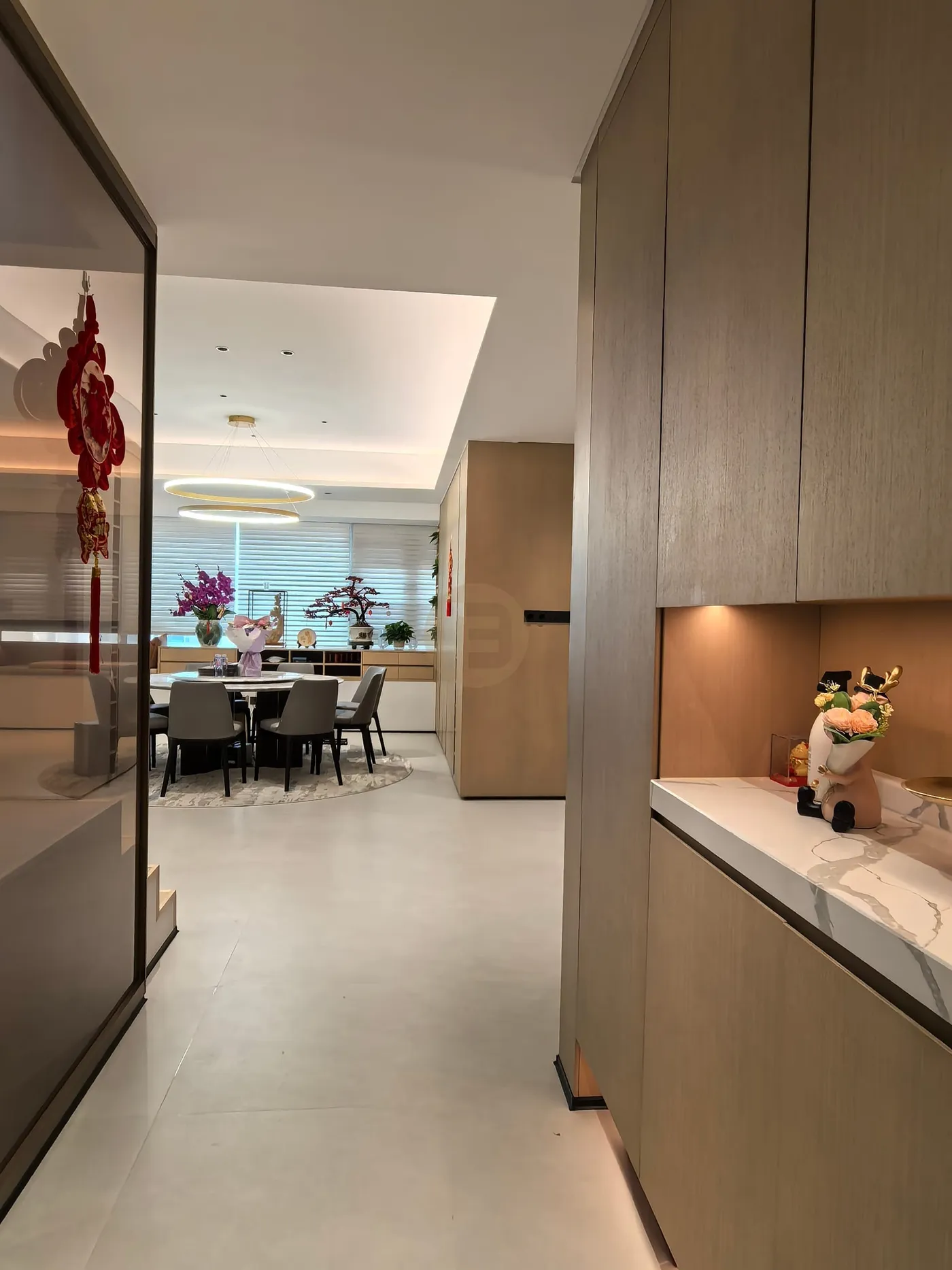 Full-height woodgrain cabinetry and a stone-topped sideboard with lit niches flanking the dining area