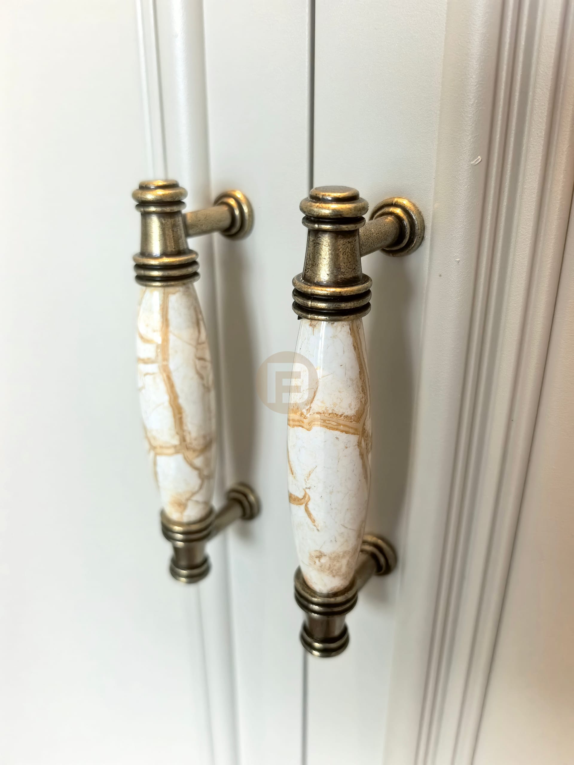 Antique-finished ceramic and brass handles with a marbled glaze on white wardrobe doors