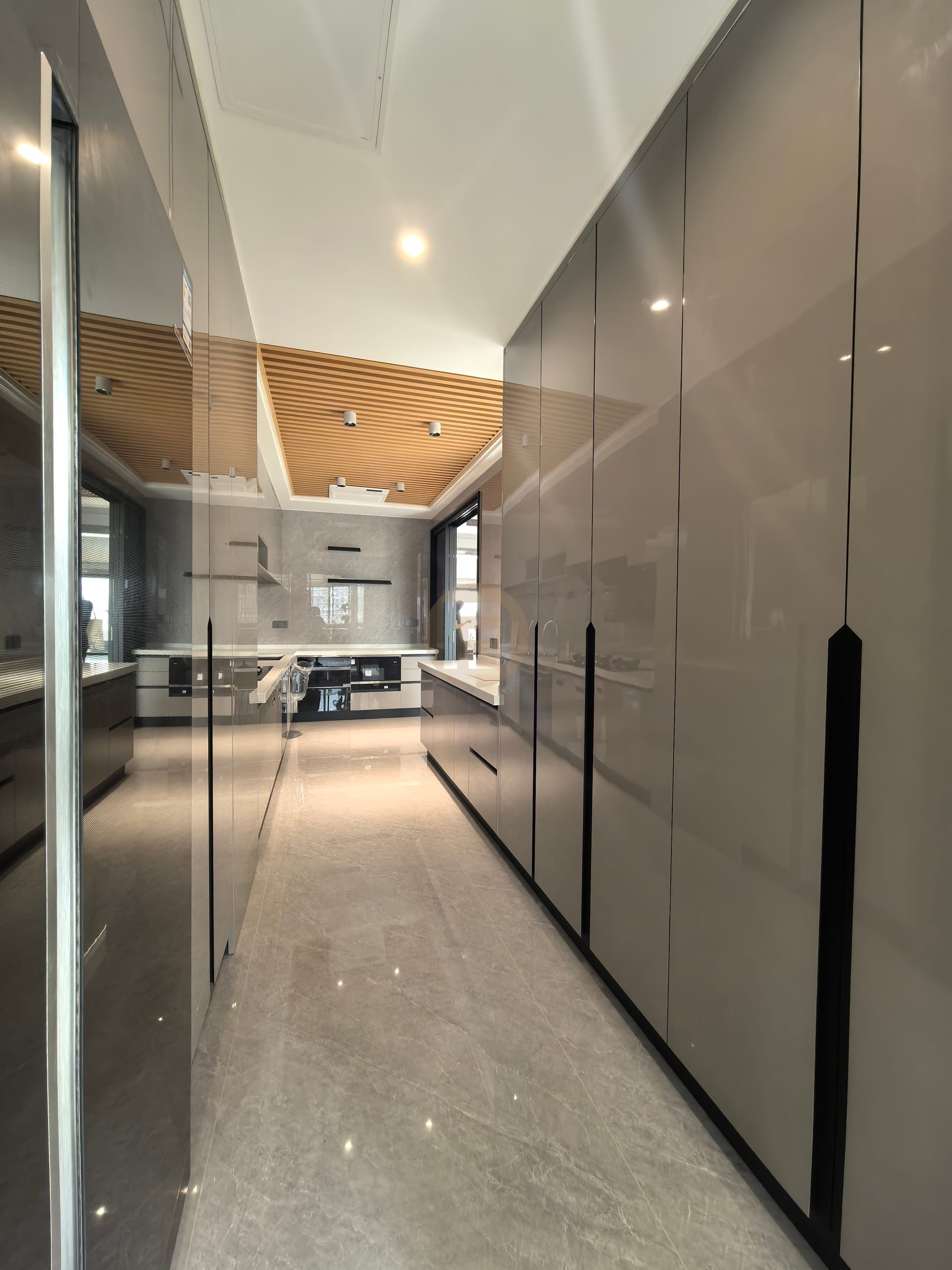 High-gloss taupe pantry cabinetry lining the passage into the main kitchen