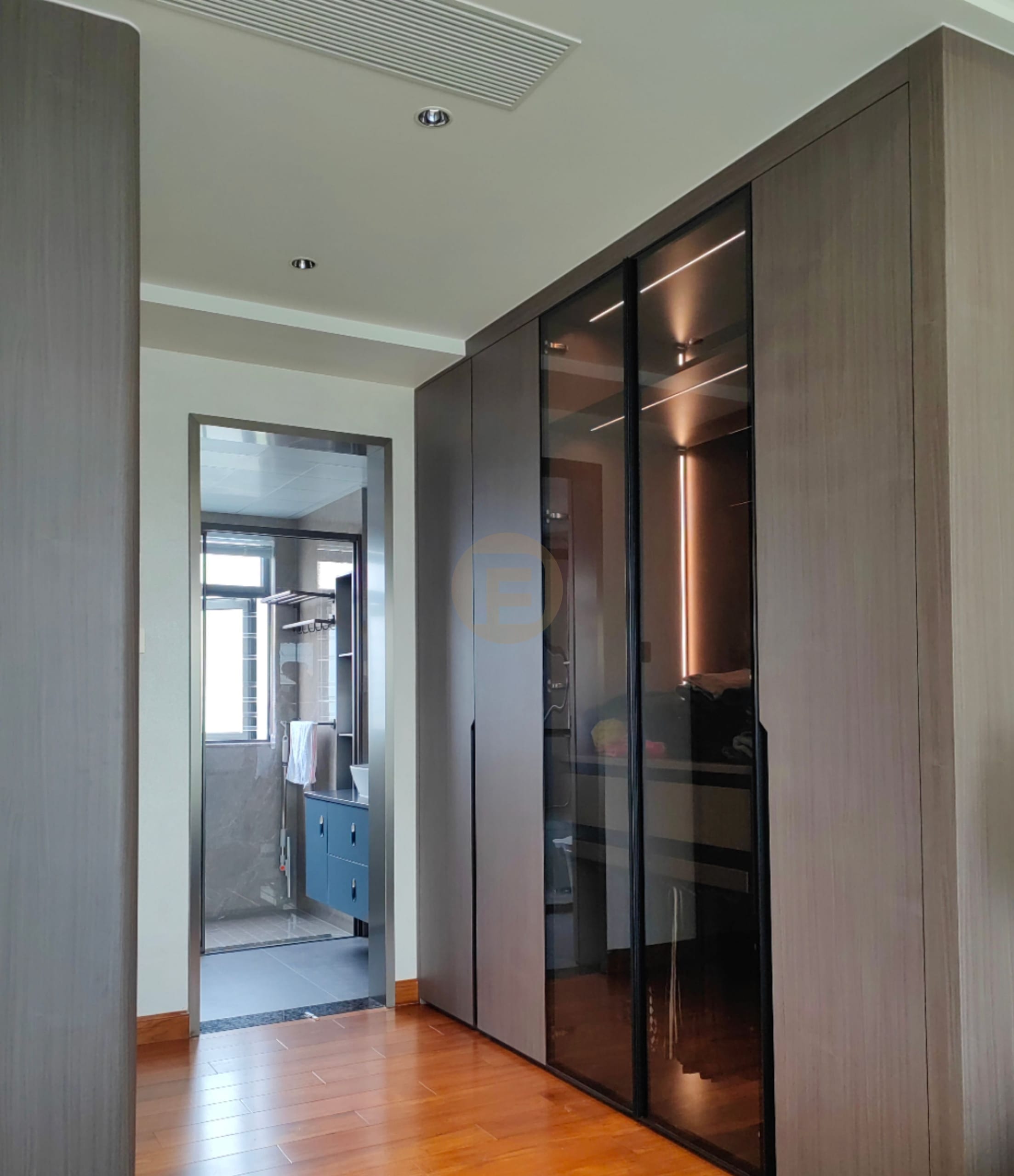 Hallway wardrobe in wood-grain stainless steel with smoked-glass doors, looking through to the bathroom