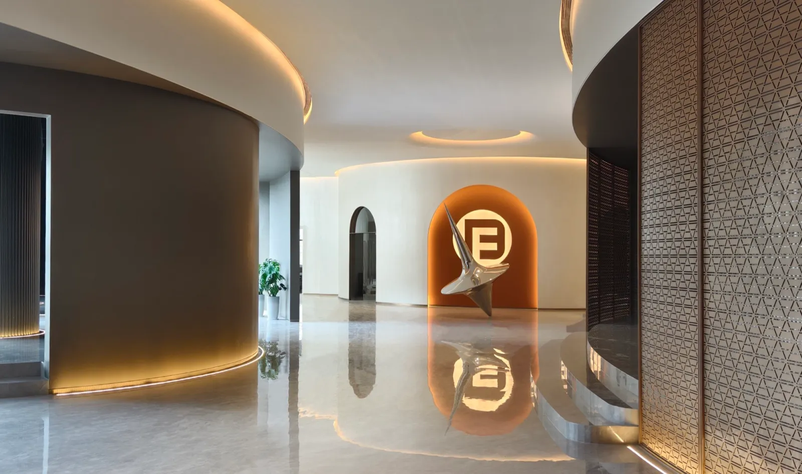 Curved entrance hall at Fadior's Foshan showroom with a reflective floor and an orange-lit sculpture.