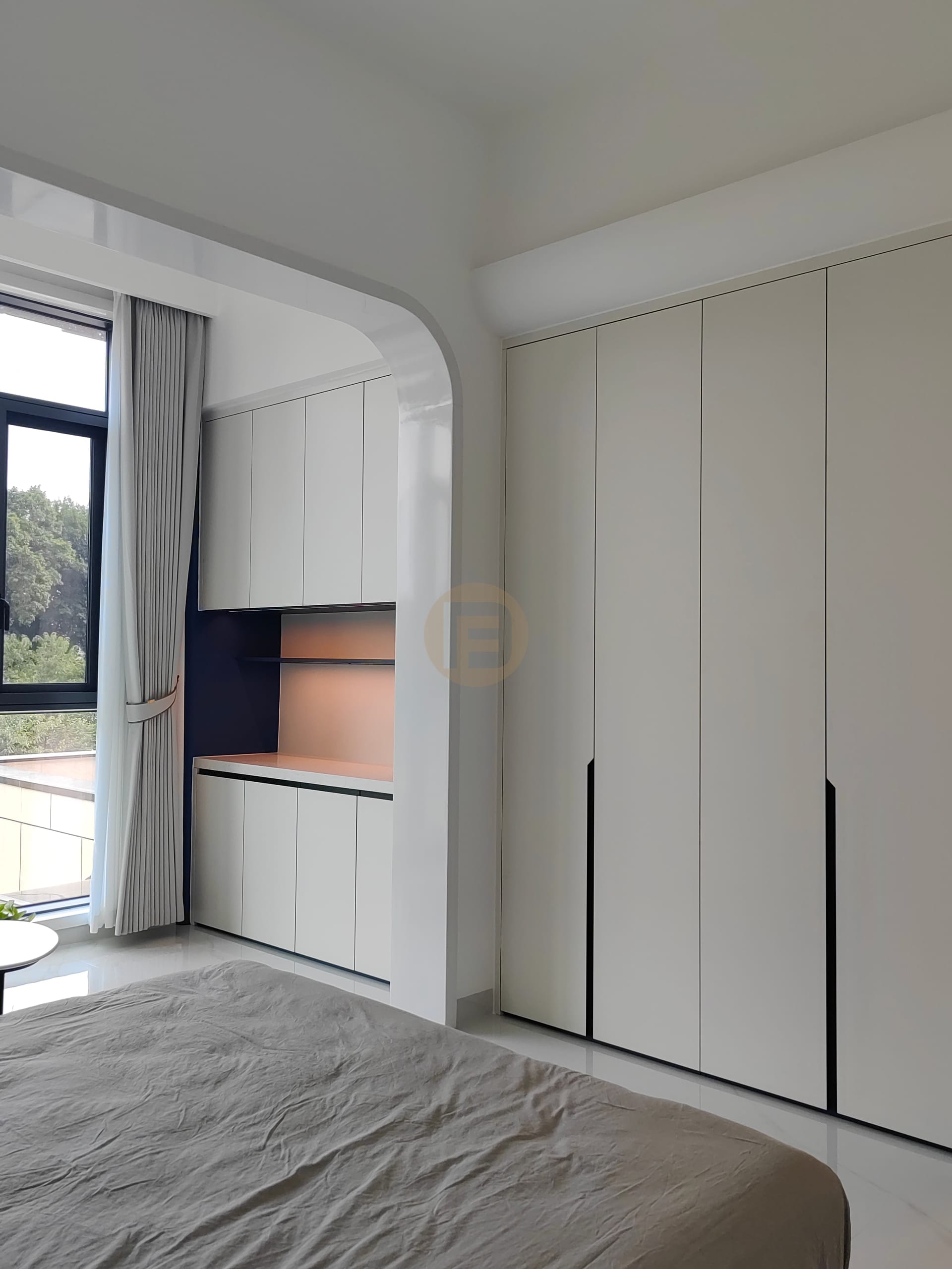 Bedroom wardrobe wall in warm white with a lit dressing niche beside the window