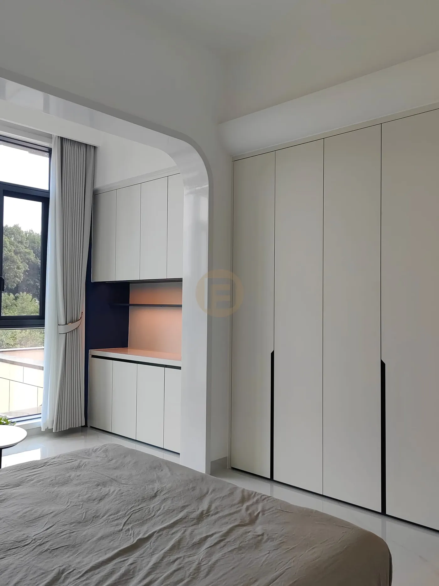 Bedroom wardrobe wall in warm white with a lit dressing niche beside the window