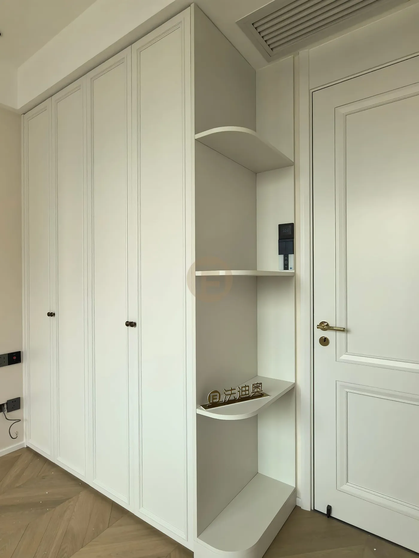 Cream paneled wardrobe with curved open corner shelves beside a classical paneled door