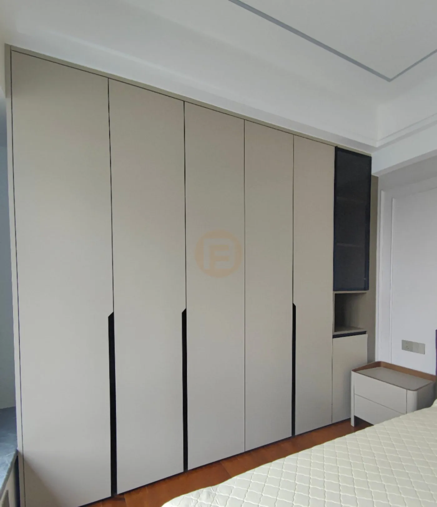 Floor-to-ceiling greige stainless steel wardrobes with recessed pulls and a smoked-glass display column in the bedroom