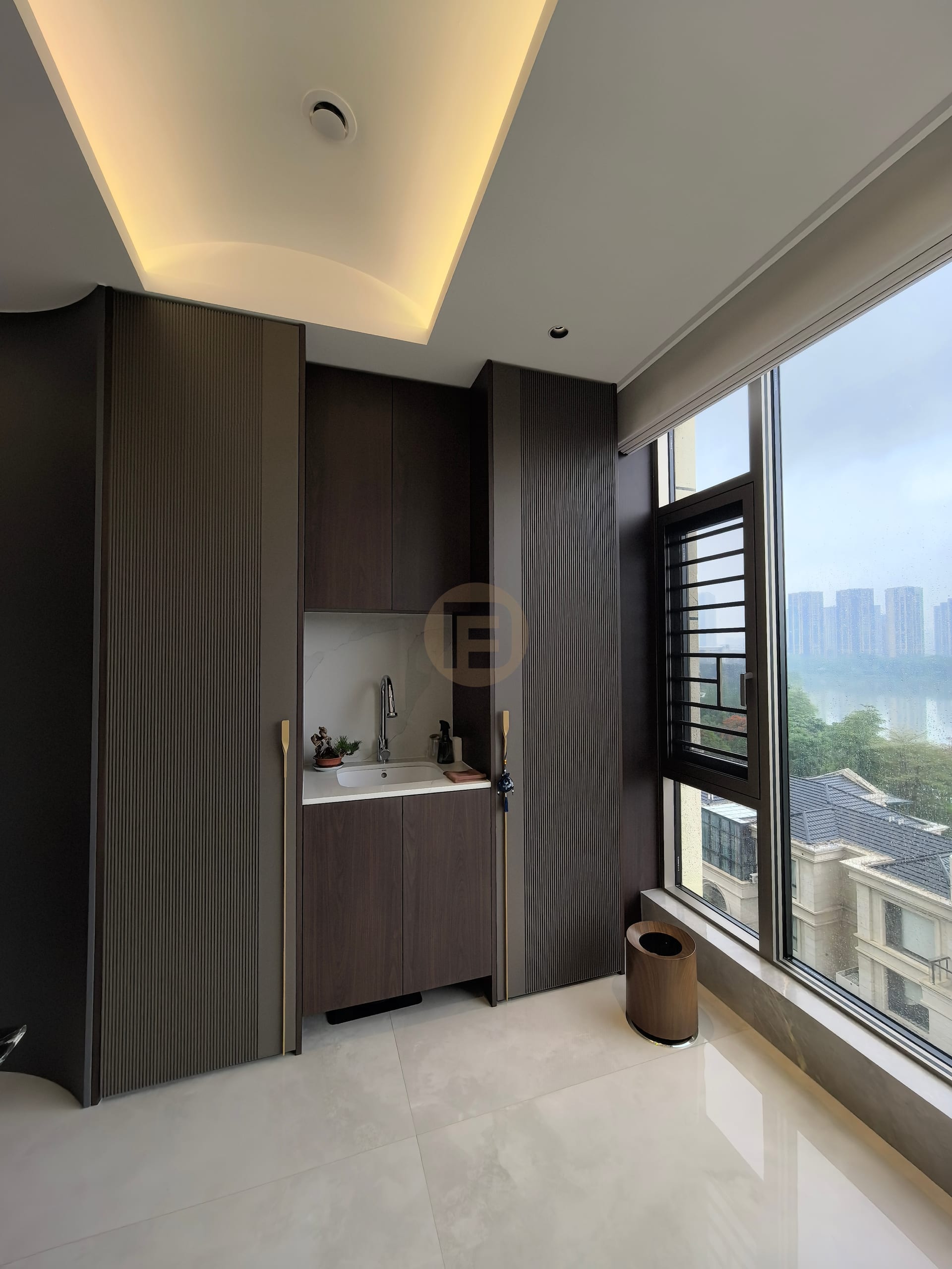 Balcony tea point in dark wood-grain stainless steel cabinetry with marble splashback and city view