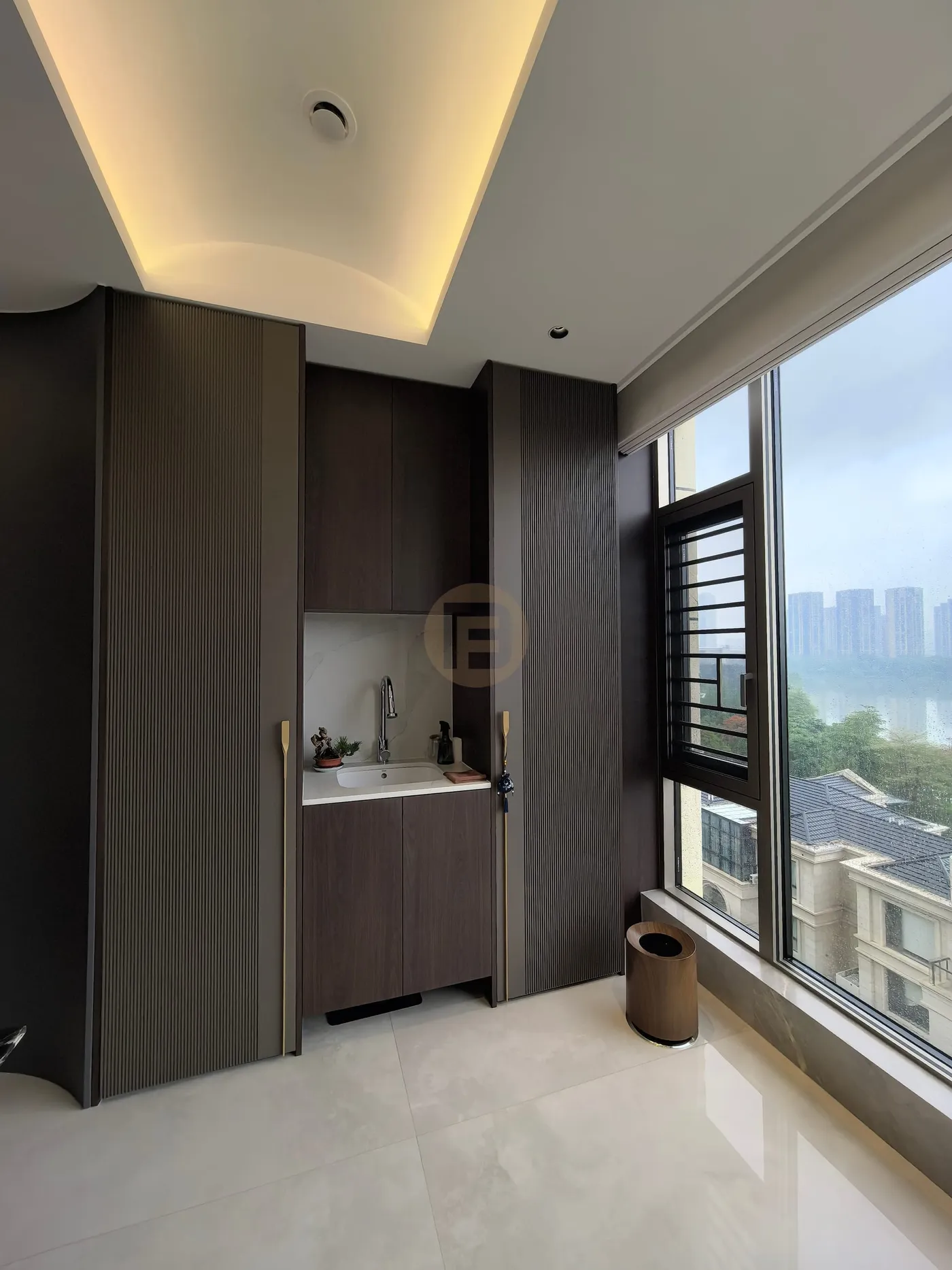 Balcony tea point in dark wood-grain stainless steel cabinetry with marble splashback and city view