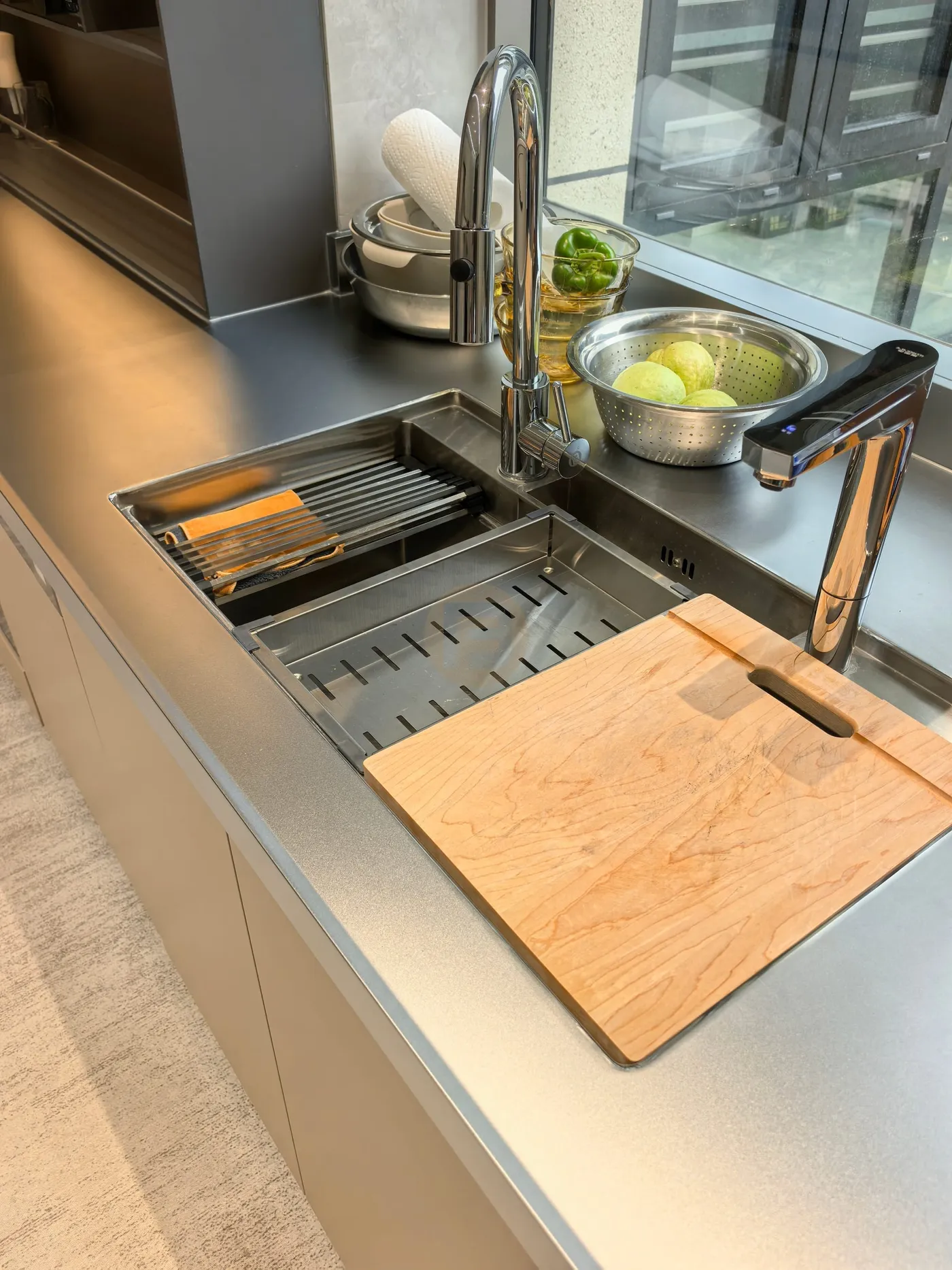 Sink welded seamlessly into the stainless steel worktop, with drainer rack and maple chopping board