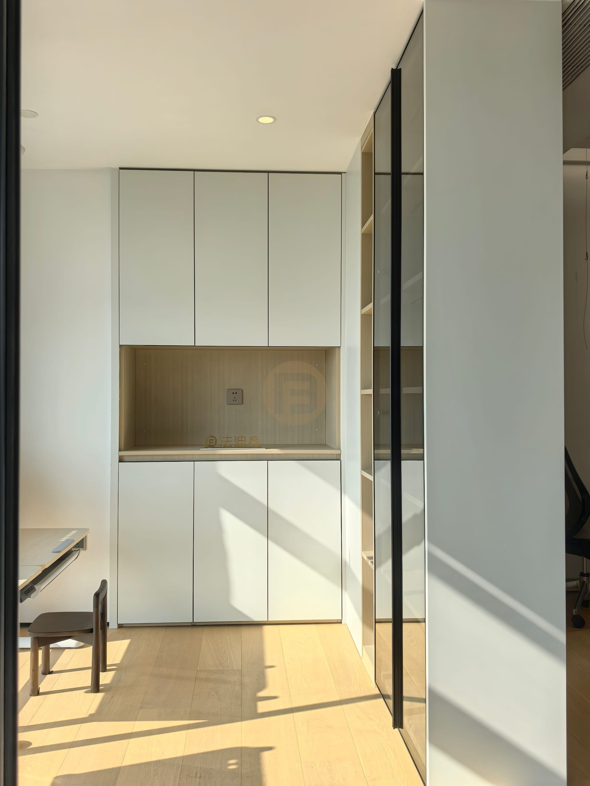 Study wall with white cabinetry, oak counter niche and a black-framed glass bookcase