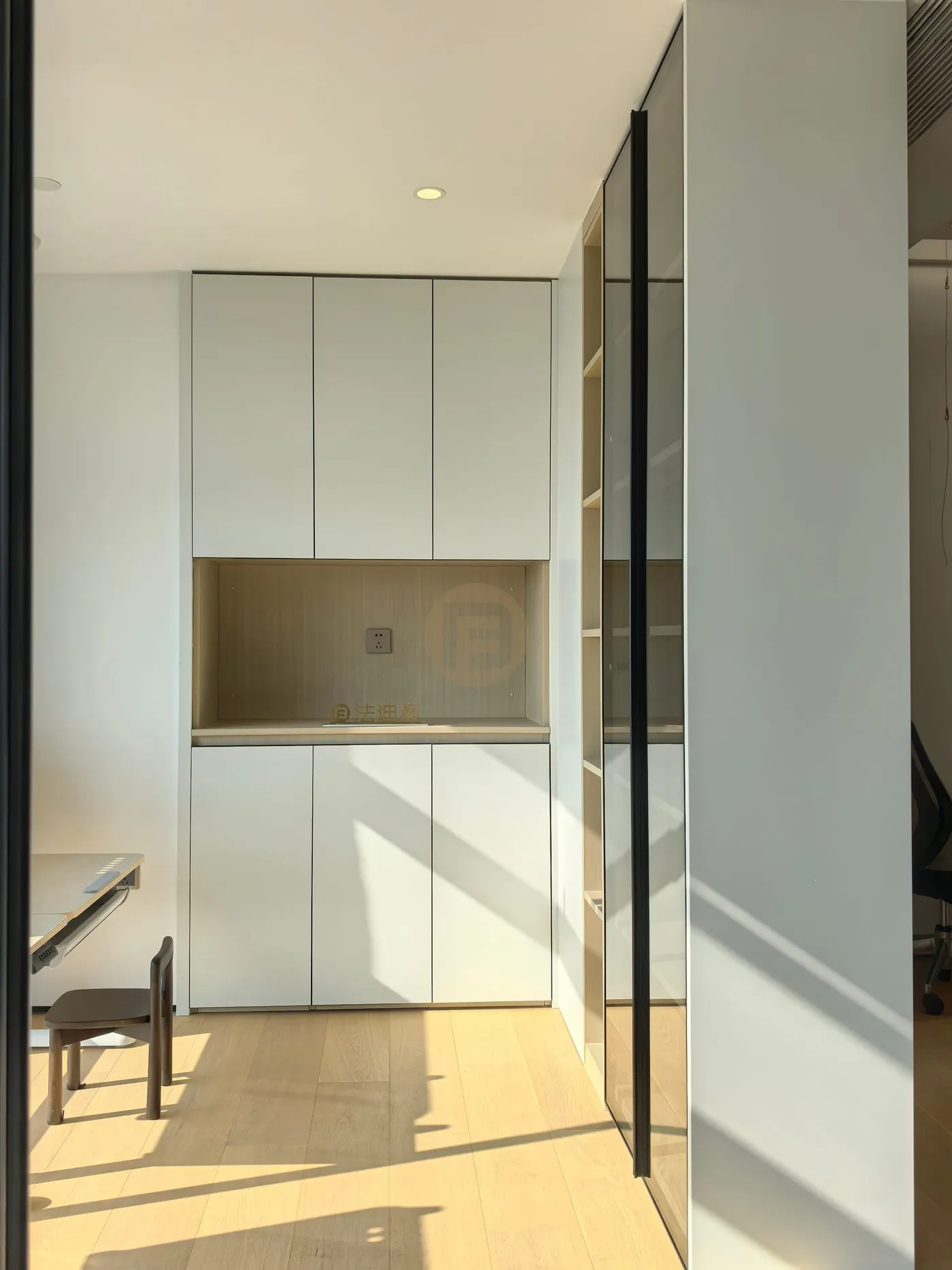 Study wall with white cabinetry, oak counter niche and a black-framed glass bookcase