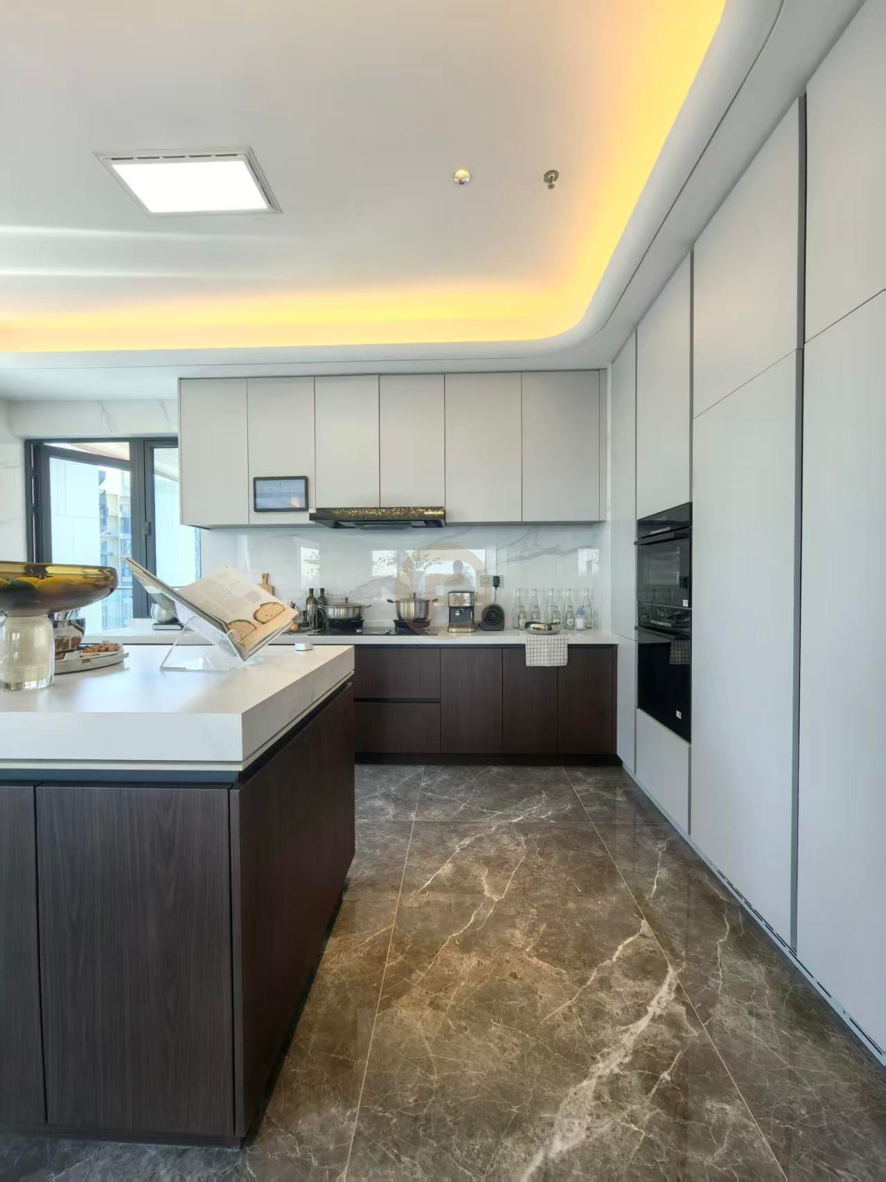 Kitchen corner with white upper cabinets, walnut-tone base units and integrated black ovens