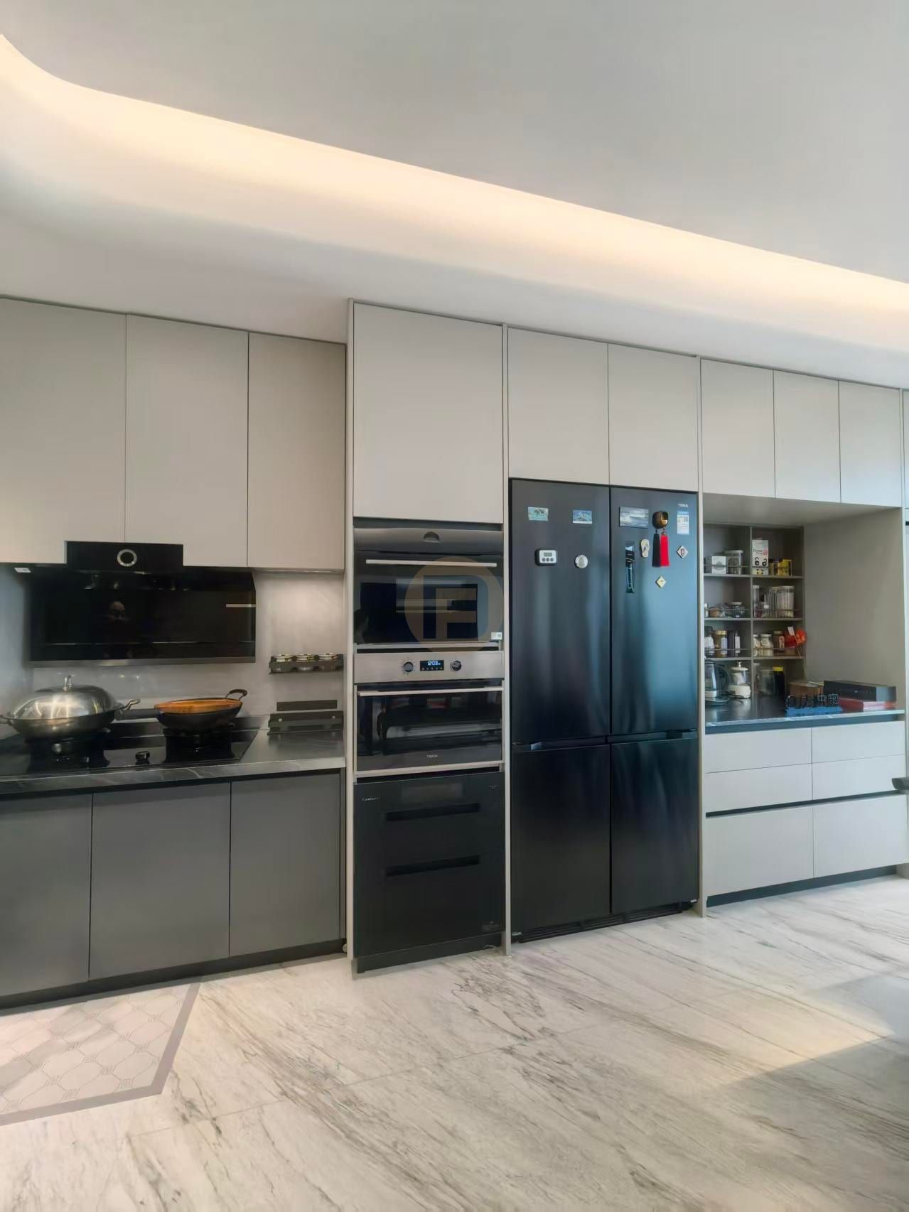 Champagne-greige stainless steel kitchen cabinetry with full-height black appliance column and marble floor
