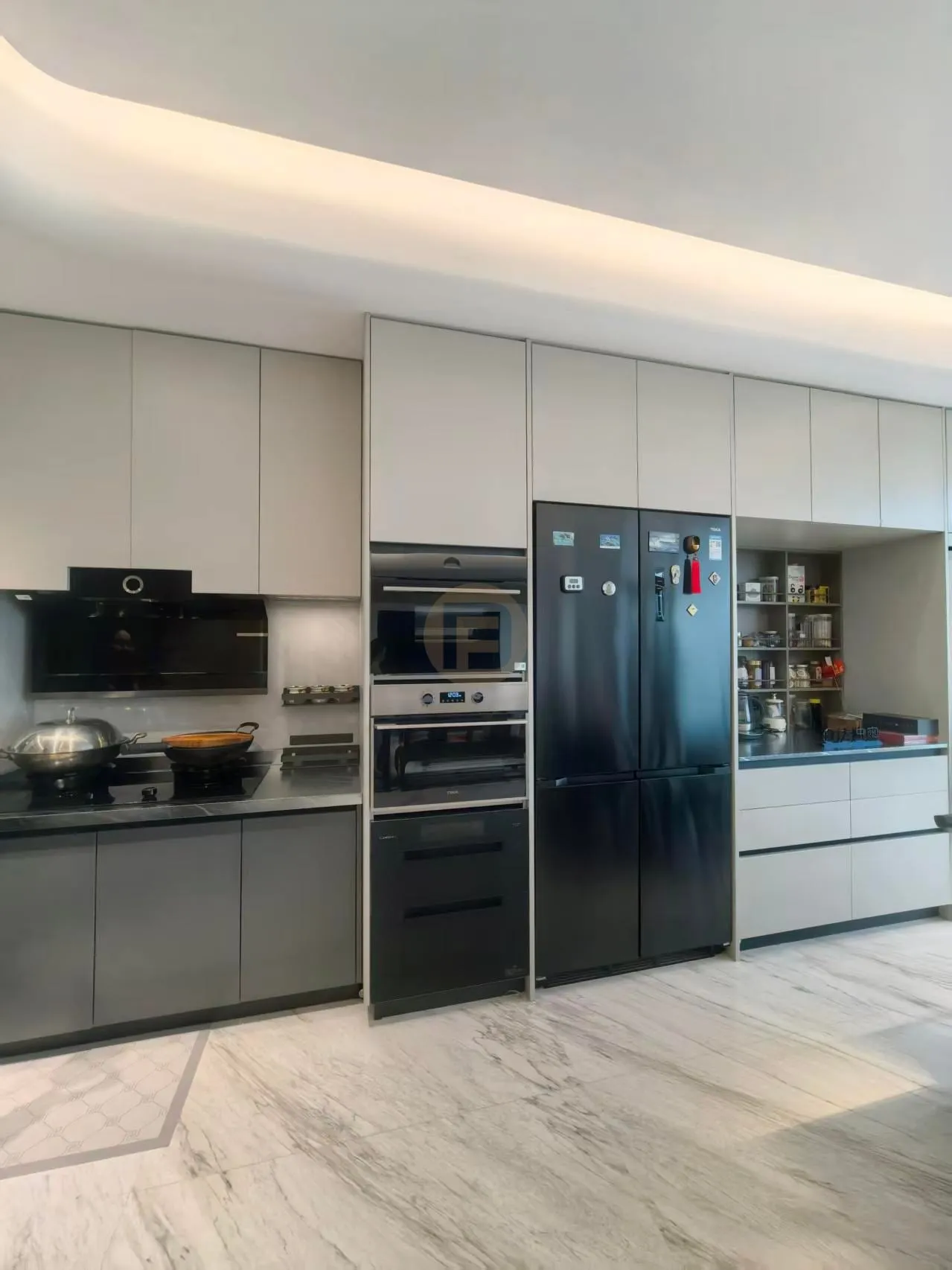 Champagne-greige stainless steel kitchen cabinetry with full-height black appliance column and marble floor