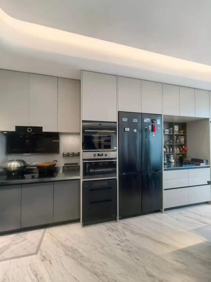 Champagne-greige stainless steel kitchen cabinetry with full-height black appliance column and marble floor