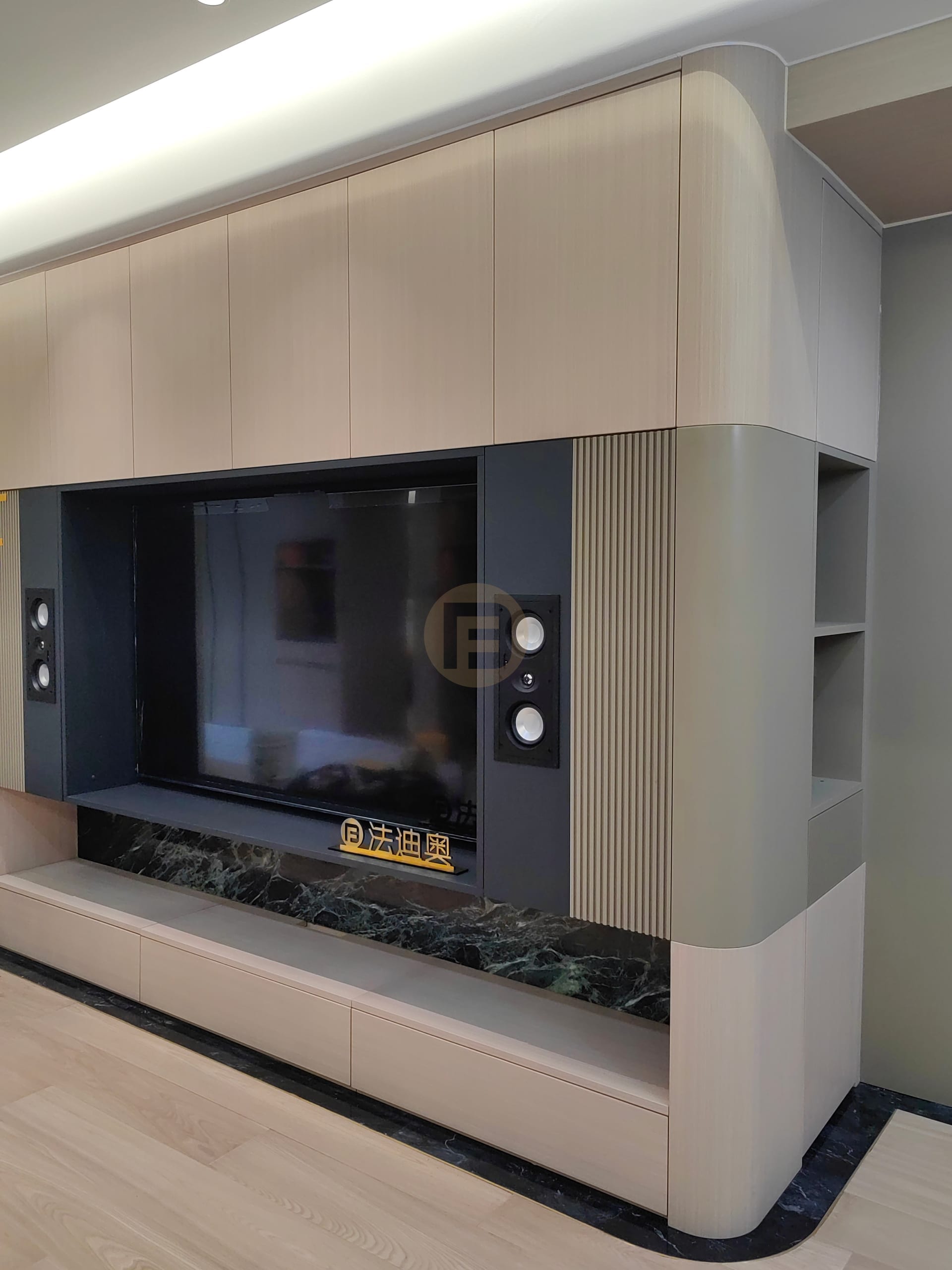 Living room media wall with fluted stainless steel panels, in-wall speakers and green marble plinth
