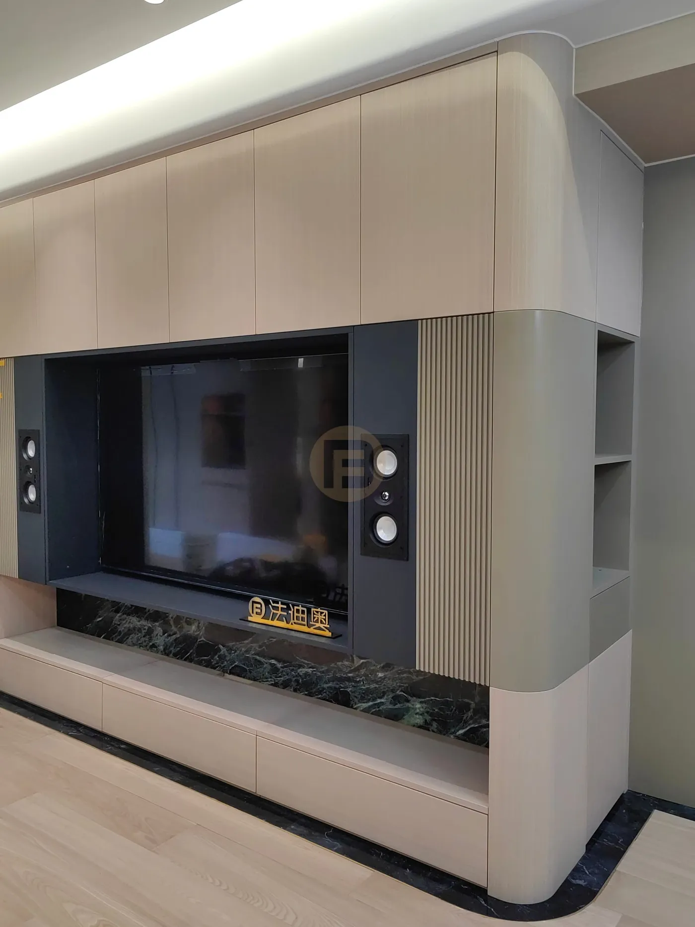 Living room media wall with fluted stainless steel panels, in-wall speakers and green marble plinth
