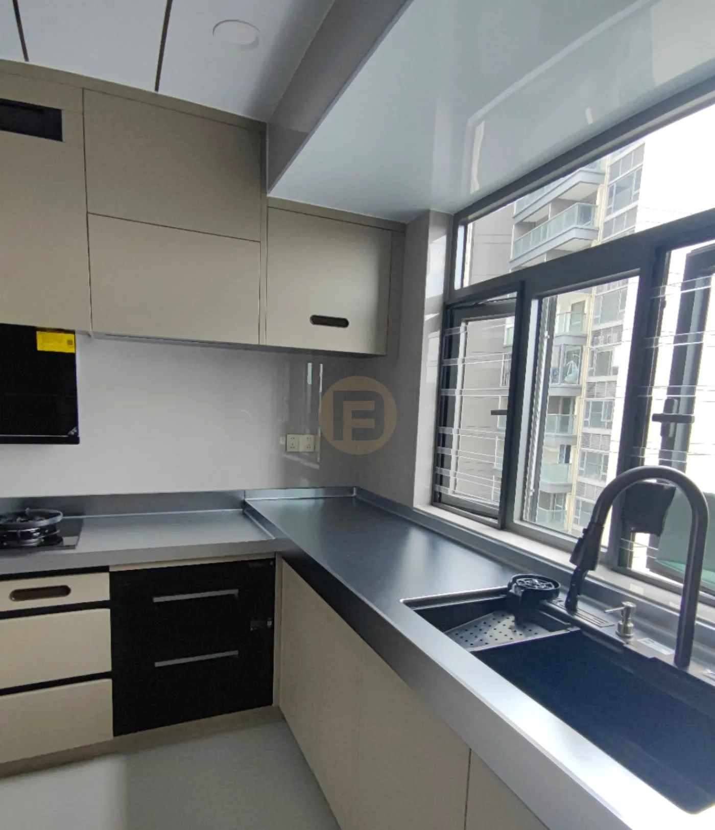Stainless steel countertop wrapping a corner window, with black undermount sink and pull-down faucet