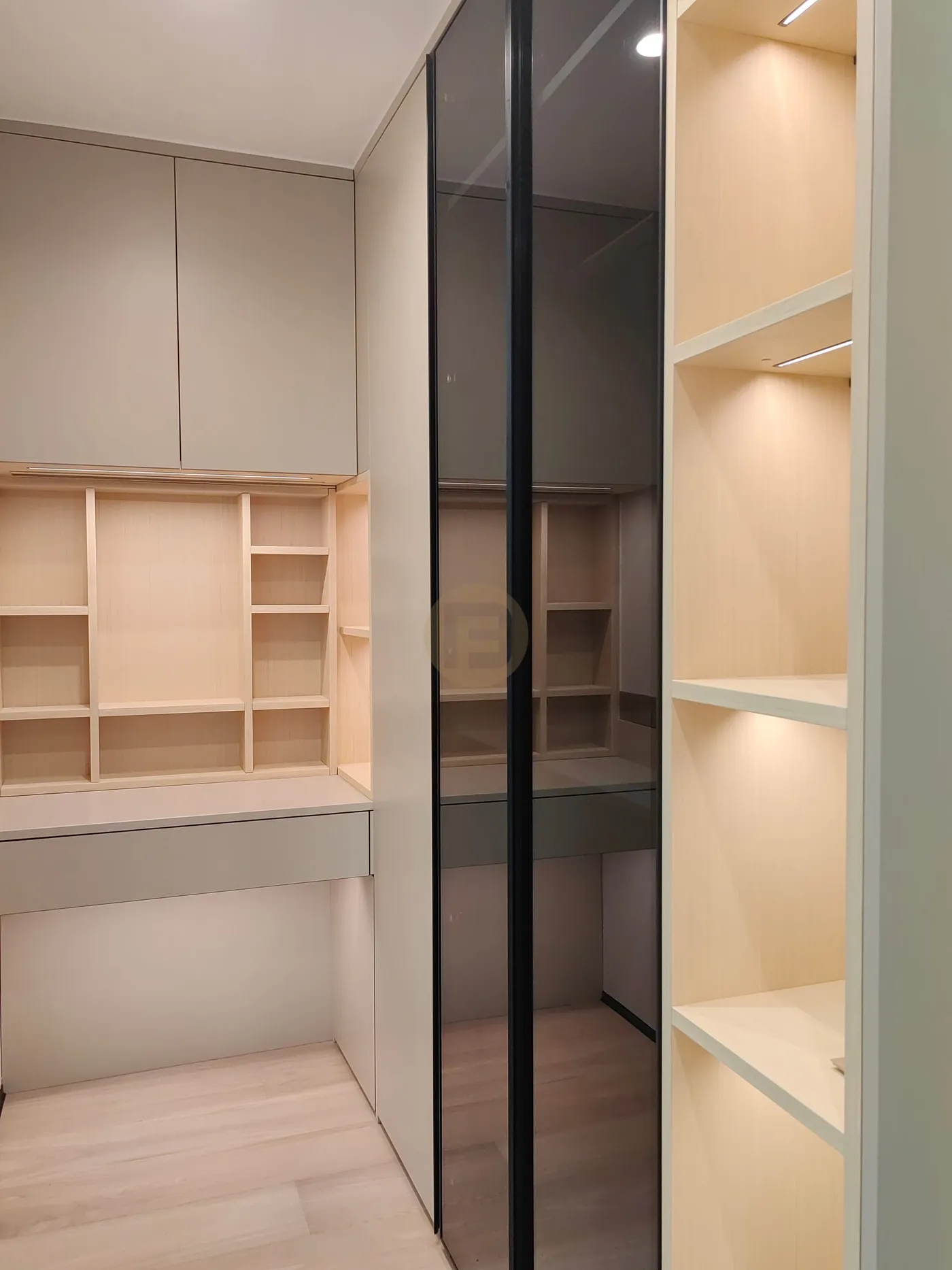 Walk-in closet with smoked-glass sliding doors, open display shelving and built-in dresser desk