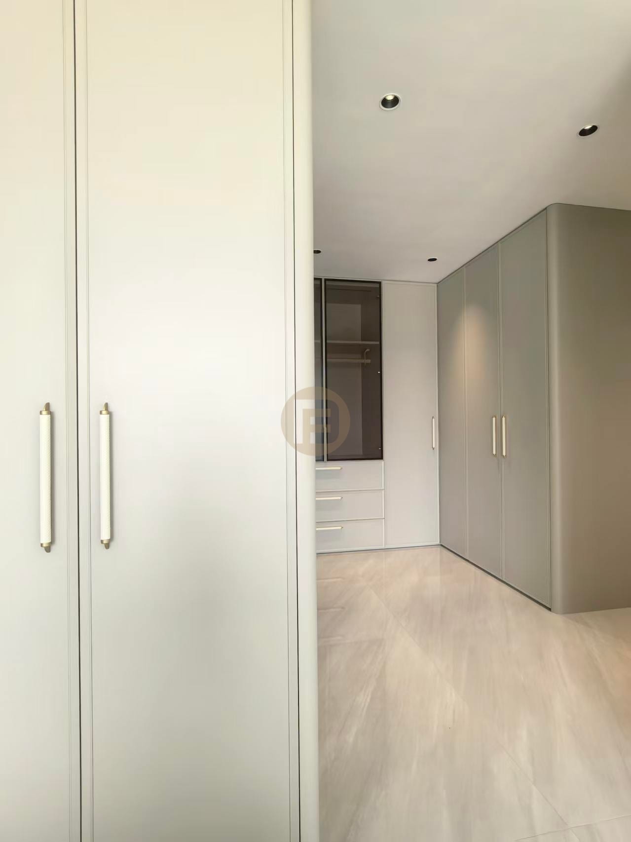 Sage-grey wardrobe run with slim metal pulls along a dressing corridor