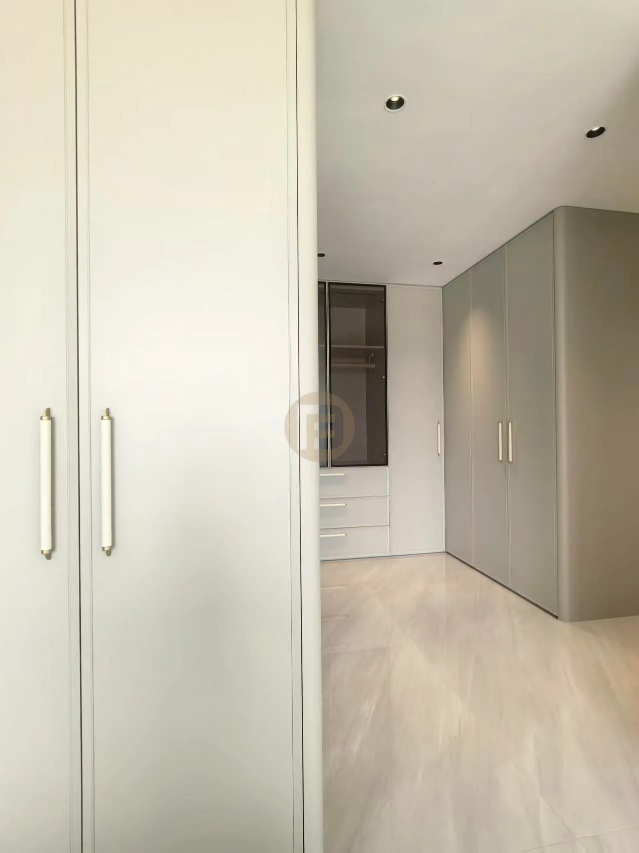 Sage-grey wardrobe run with slim metal pulls along a dressing corridor