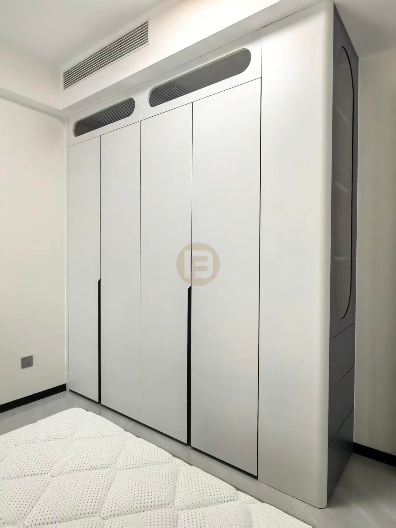 White wardrobe with louvred vent detailing and a smoked-glass display cabinet in a bedroom