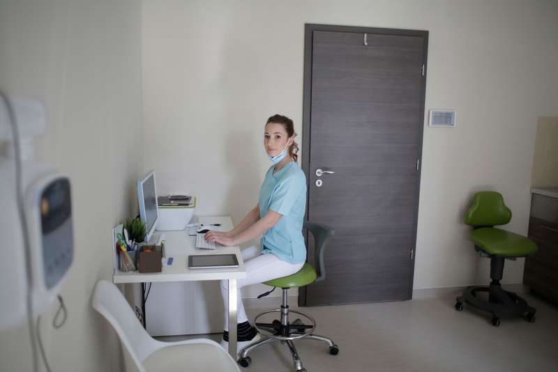 A clinic receptionist handling an online booking at a computer